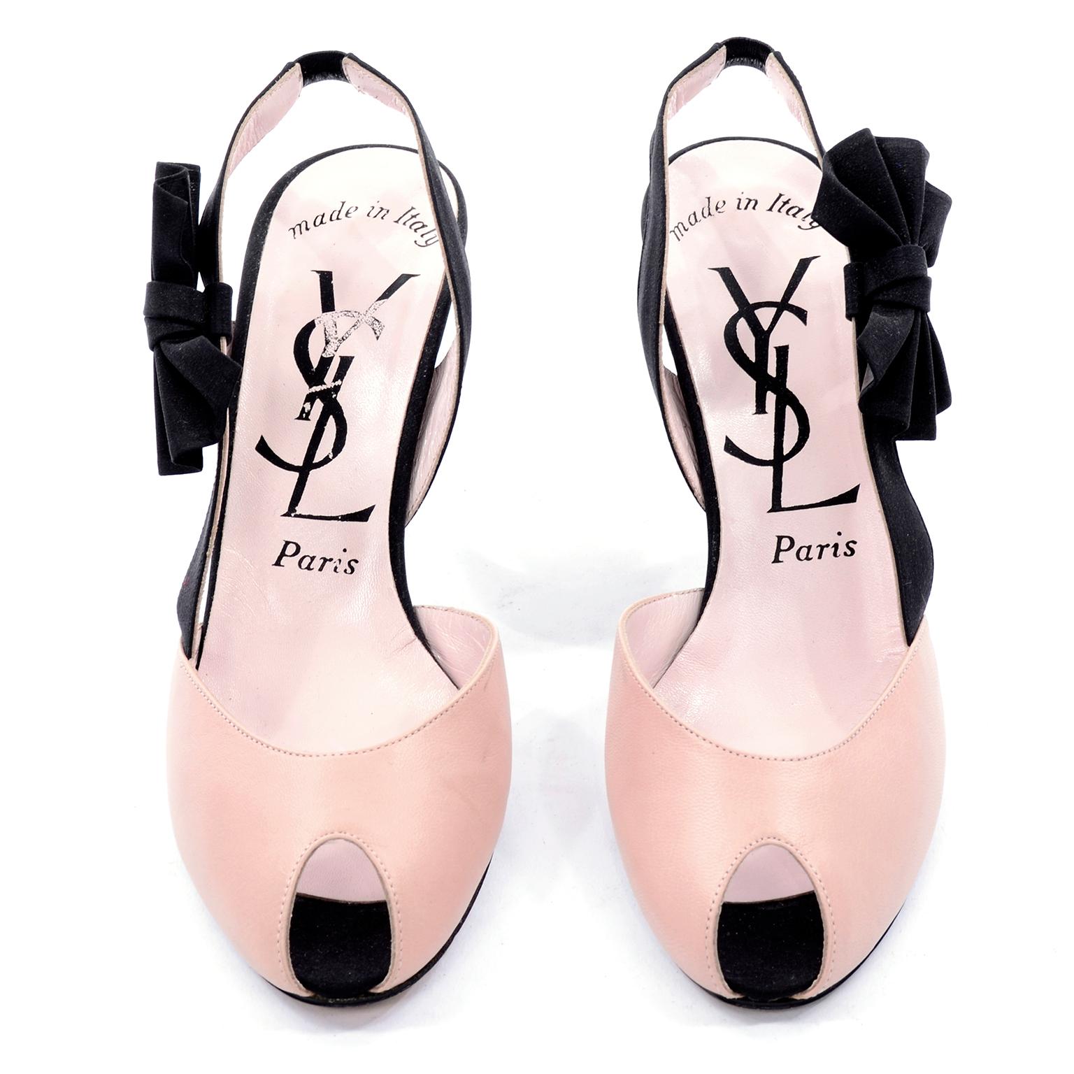 These are pink and black Yves Saint Laurent heels with a peep toe and black bow on the outer side of the slingback strap. They have pale pink leather uppers and a black strap and heel. Made in Italy.  
Size 7.5 N. 
HEEL: 3.75
