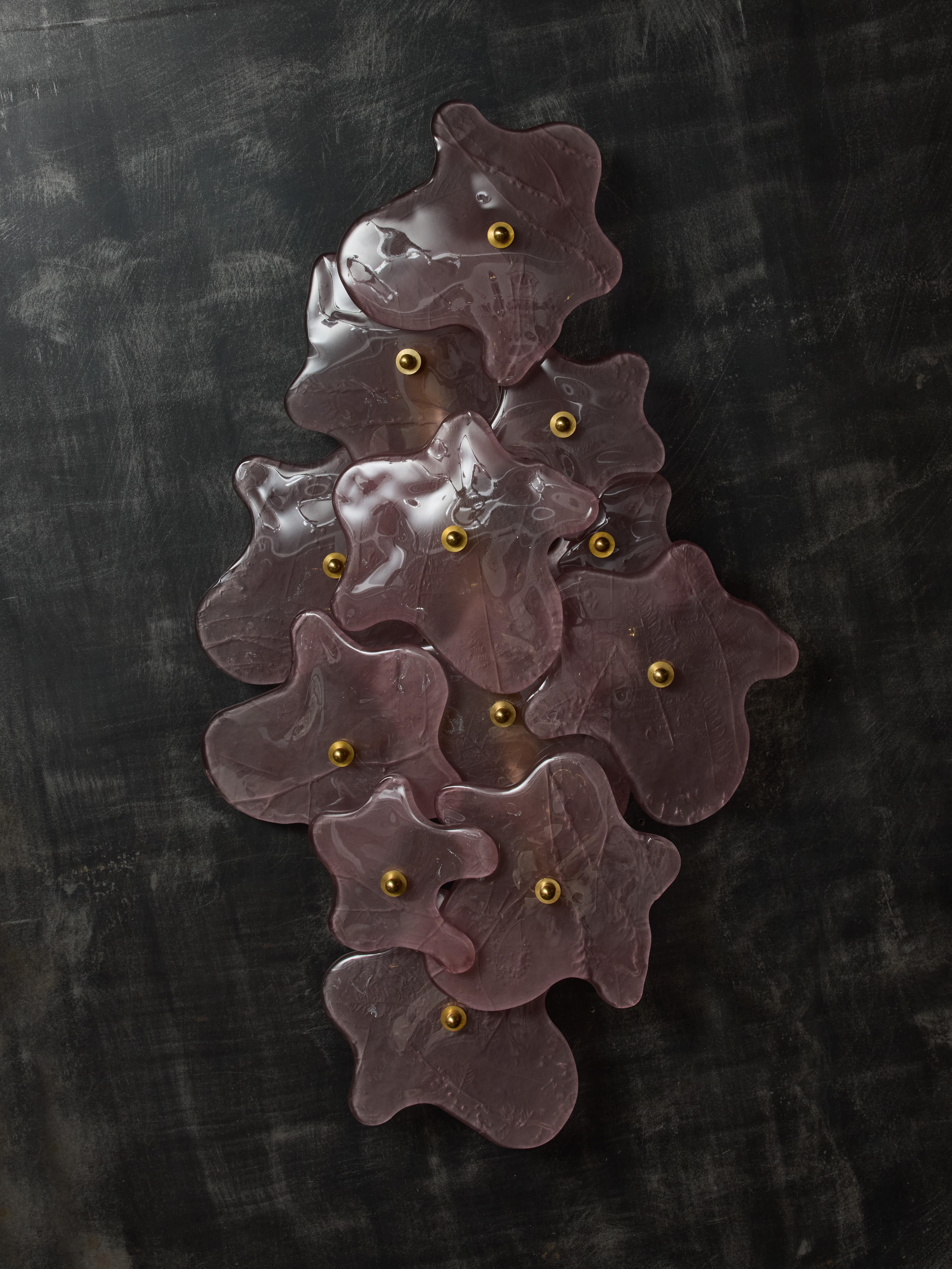 Des appliques murales de forme libre composées de couches d'éclats roses comme des pièces de verre de Murano recouvrant une structure métallique avec trois sources de lumière.

