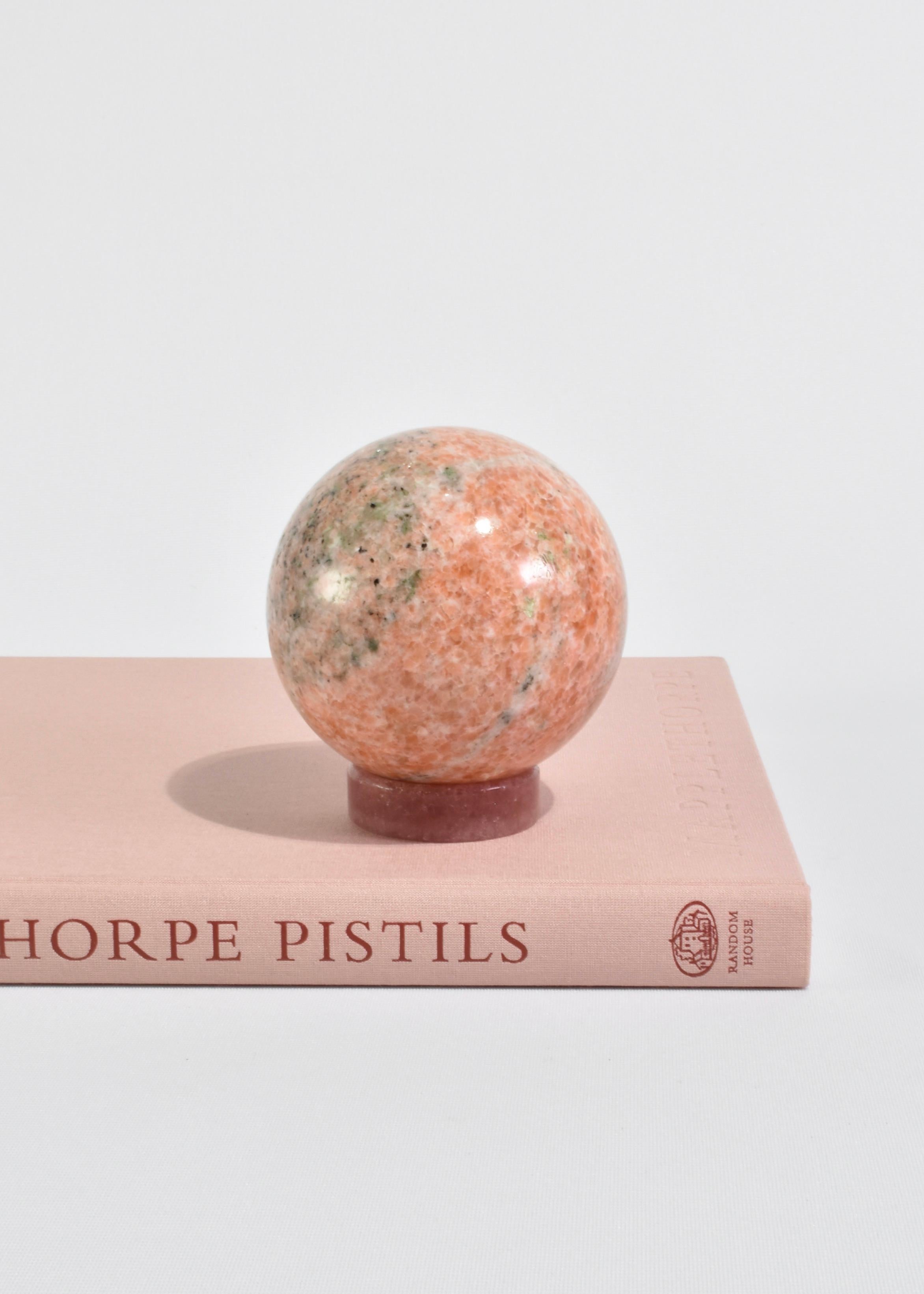 Bellissima scultura a sfera in pietra rosa su una base rimovibile.