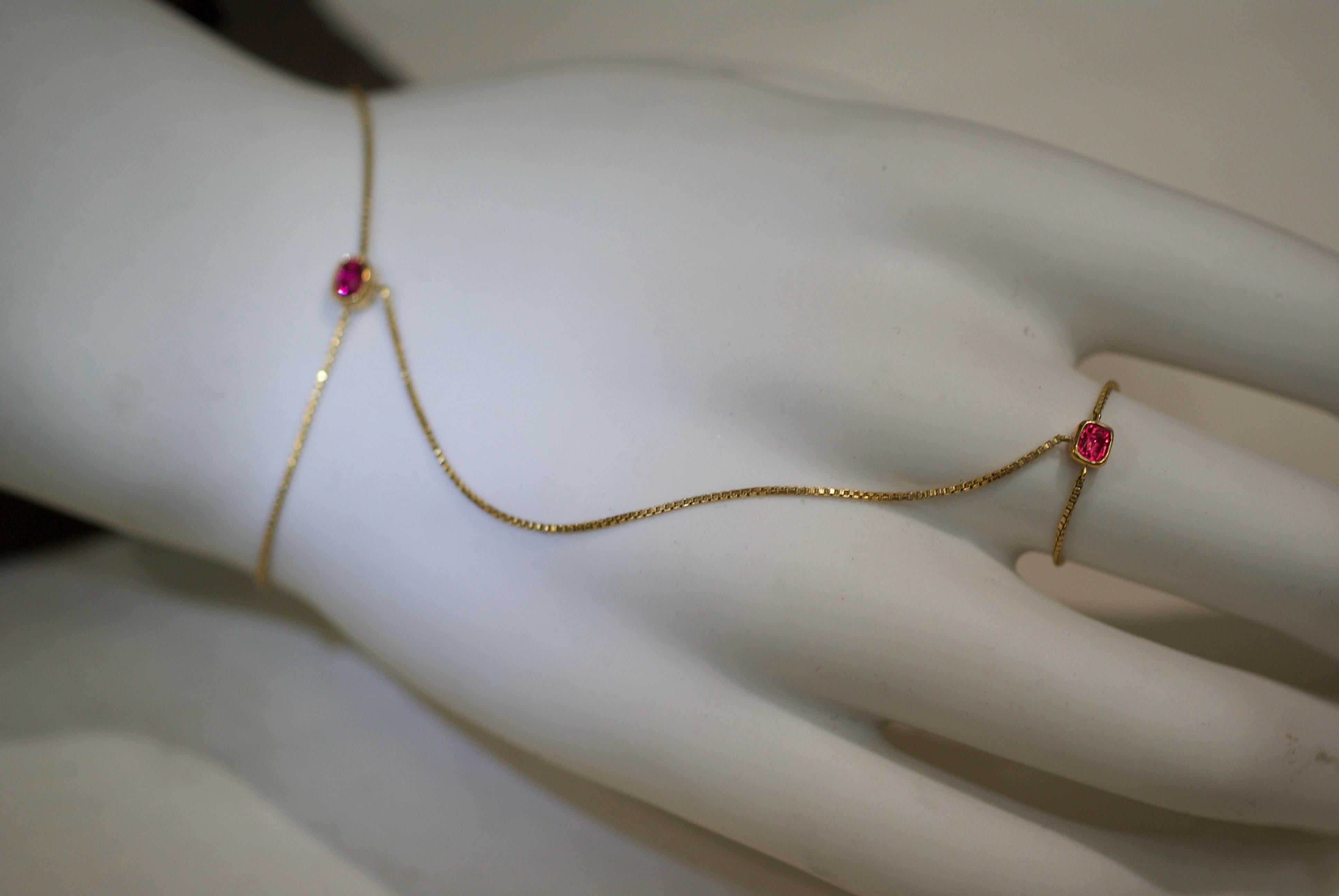 Designed as a pair of cushion-cut neon pink spinel, each within bezels, one centering a bracelet and the other connected by chain to a ring. Sinuous, sensual and elegant. Manufactured entirely in 18K gold. Made in New York City.

One photograph