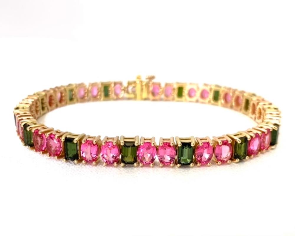 Over 15 carats of natural neon pink spinel are paired with pretty olive green tourmalines in this luxurious bracelet of stunning colored jewels. These oval spinels are gorgeous, with endless sparkle and life due to their clarity and exceptional