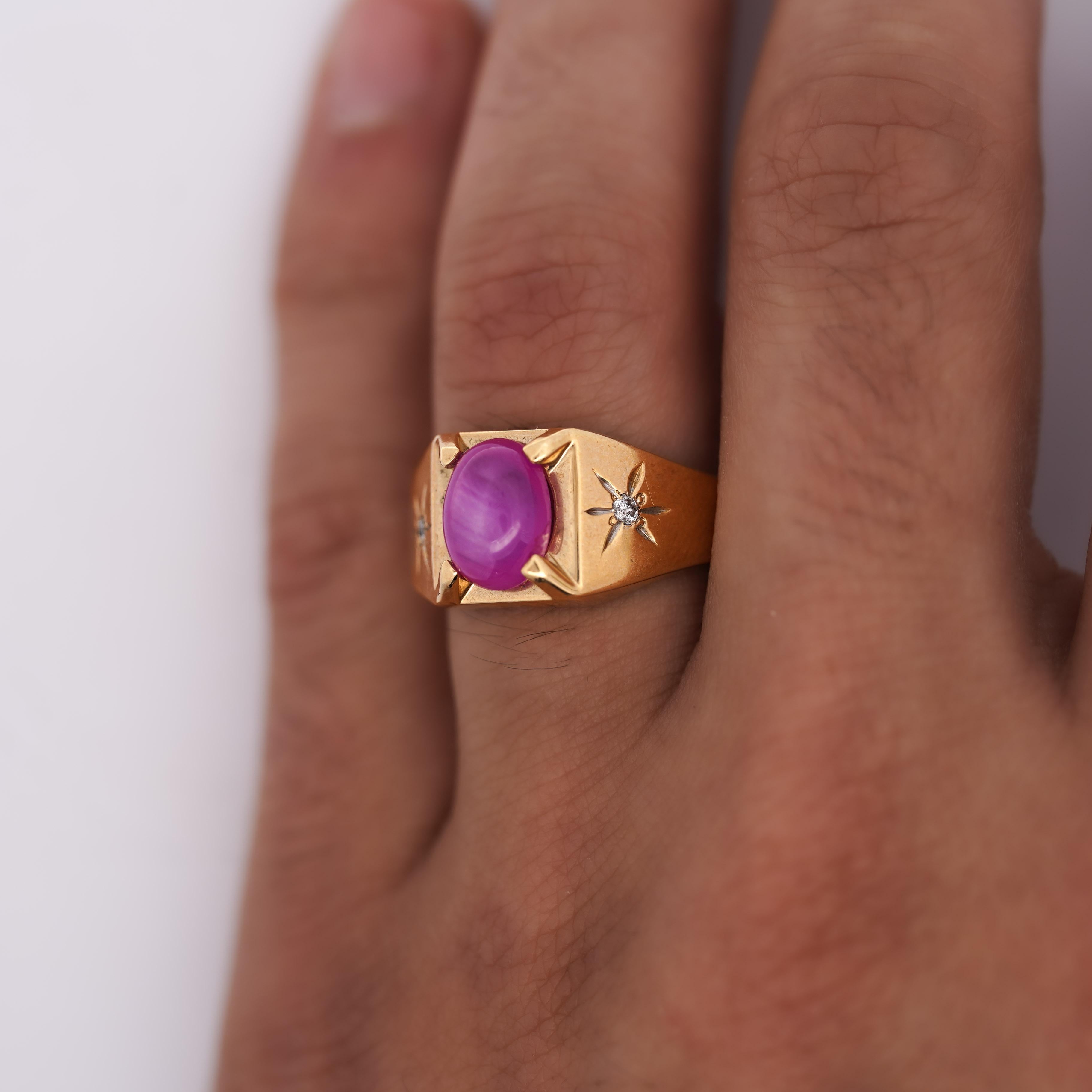 Ein auffälliger Ring aus 14 Karat Gelbgold mit einem rosafarbenen Sternsaphir, der von Diamanten in Starburst-Gravuren akzentuiert wird. Der breite, sich verjüngende Schaft verleiht diesem Stück einen starken Retro-Charakter und Stilsicherheit. Ring