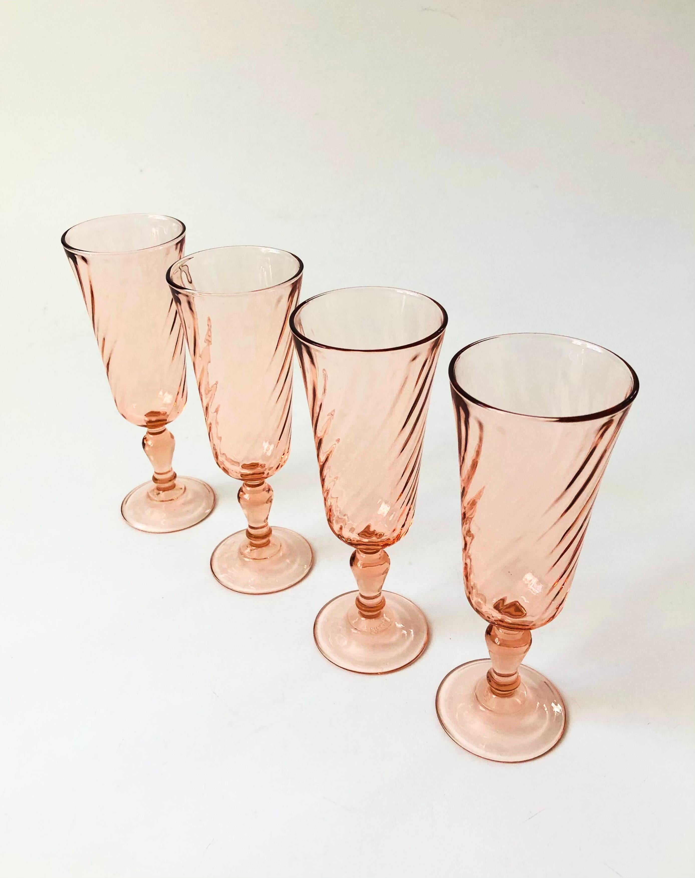 A set of 4 vintage champagne flutes in a pale blush pink hue. Each glass has a lovely swirl design. Made in France by Arcoroc.

