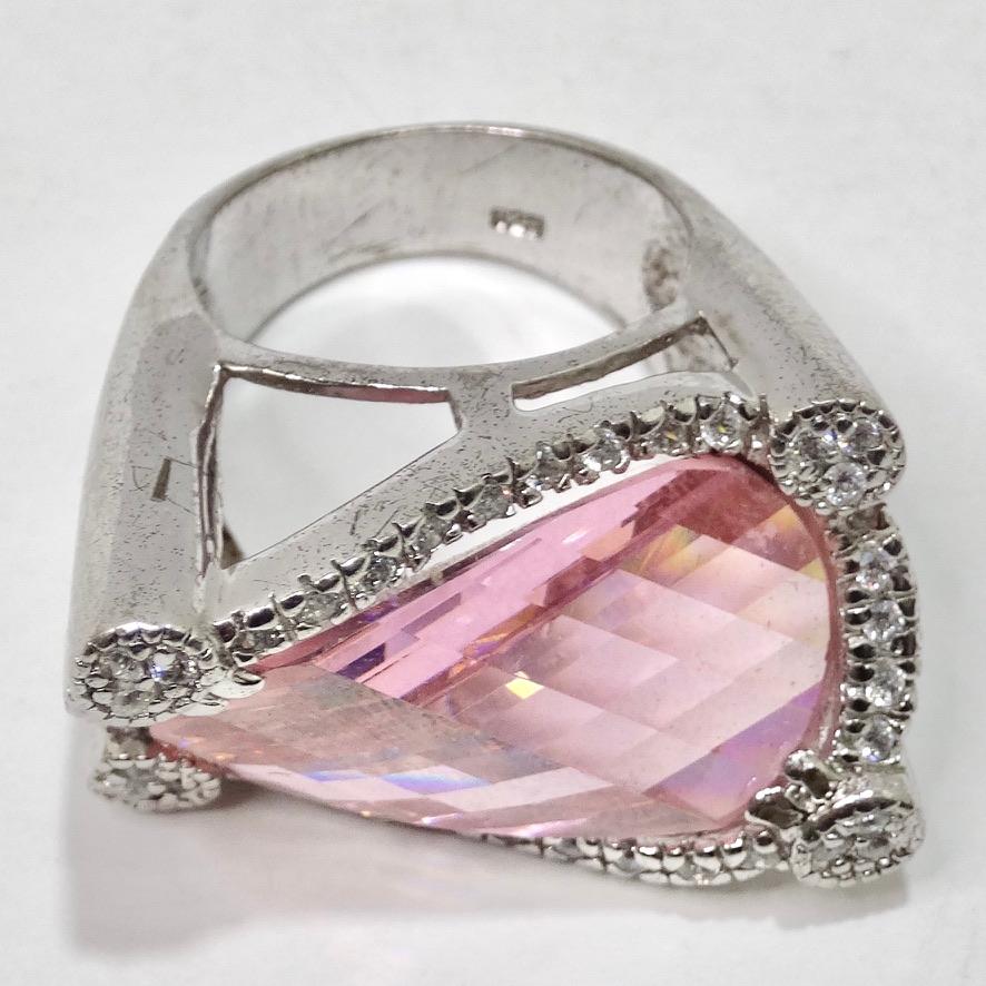 Get your hands on this eye catching statement cocktail ring circa 1980! A size 7.5 silver 925 band gives way to a large synthetic pink sapphire surrounded by white crystals. The cut of the sapphire is very abstract, look closely and notice the way