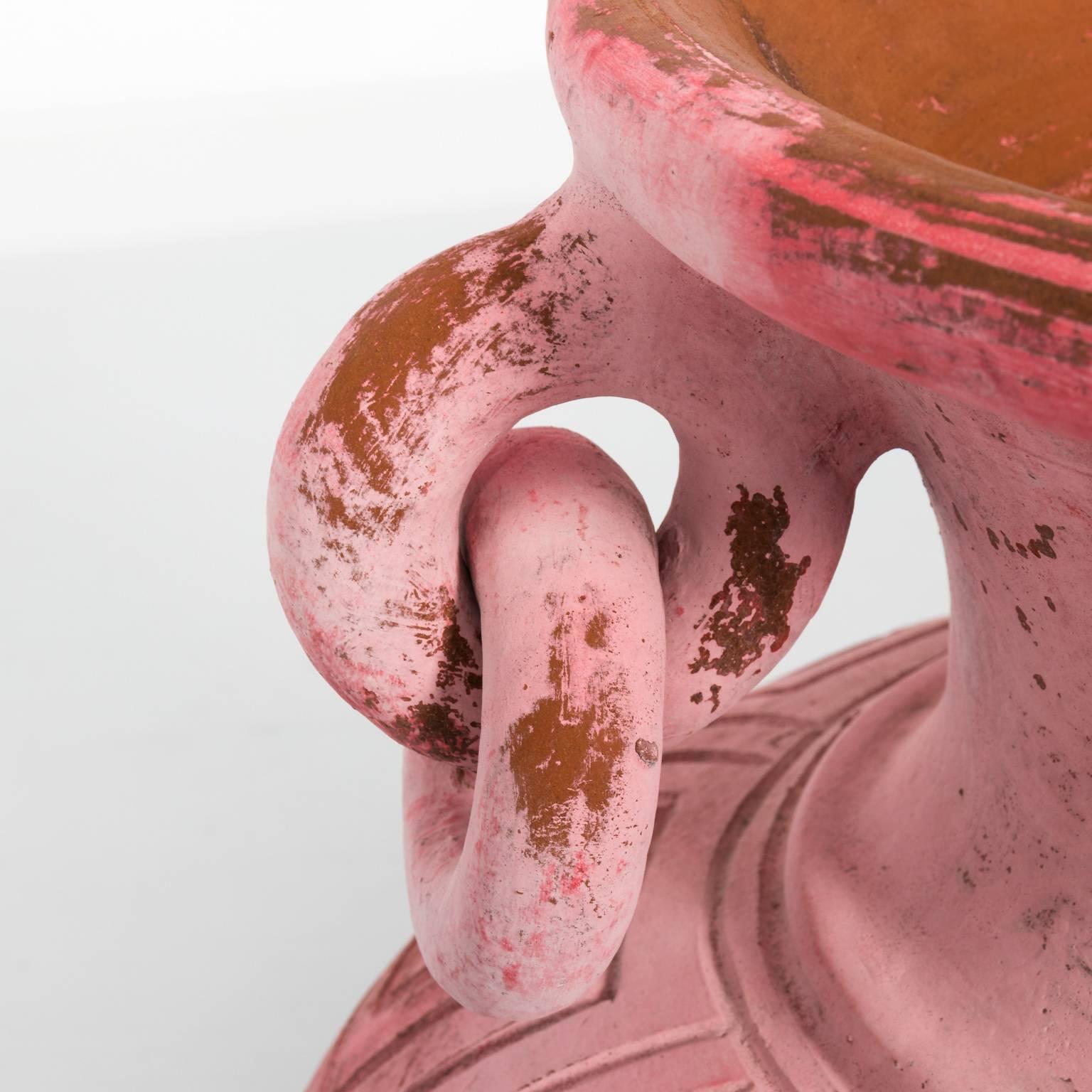 Contemporary pink painted terracotta urn with Greek key trim and double handles in a rusticated finish.
 
