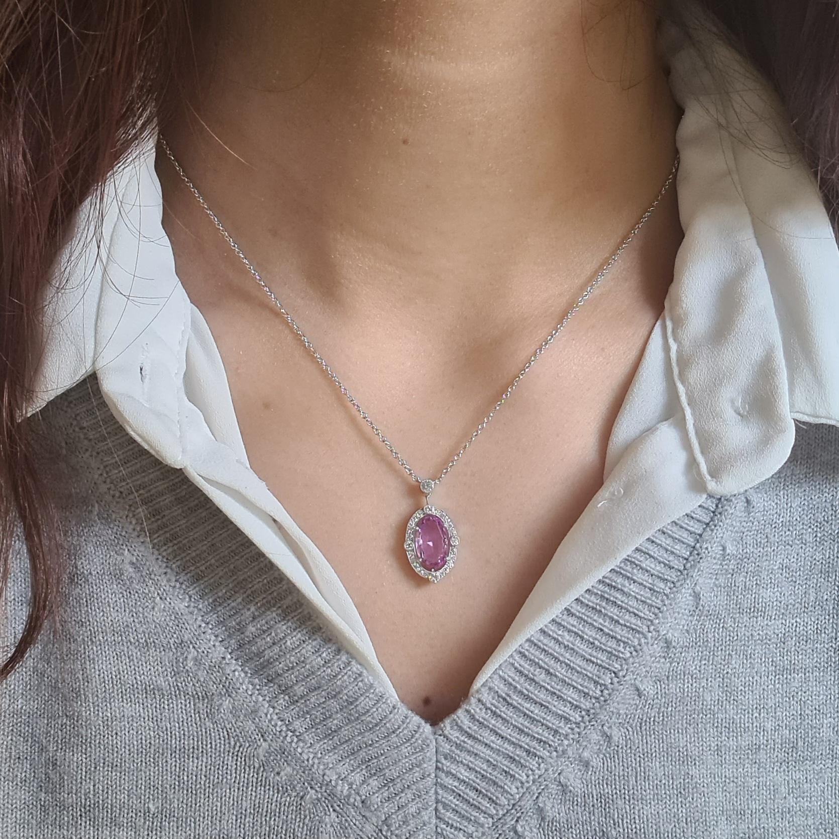 A pink topaz and diamond pendant, set with a 2.23ct, oval, faceted pink topaz, in an oval micro pavé surround, with an air gap between the centre stone and the border, set with larger round brilliant-cut diamonds on the quarters, with smaller