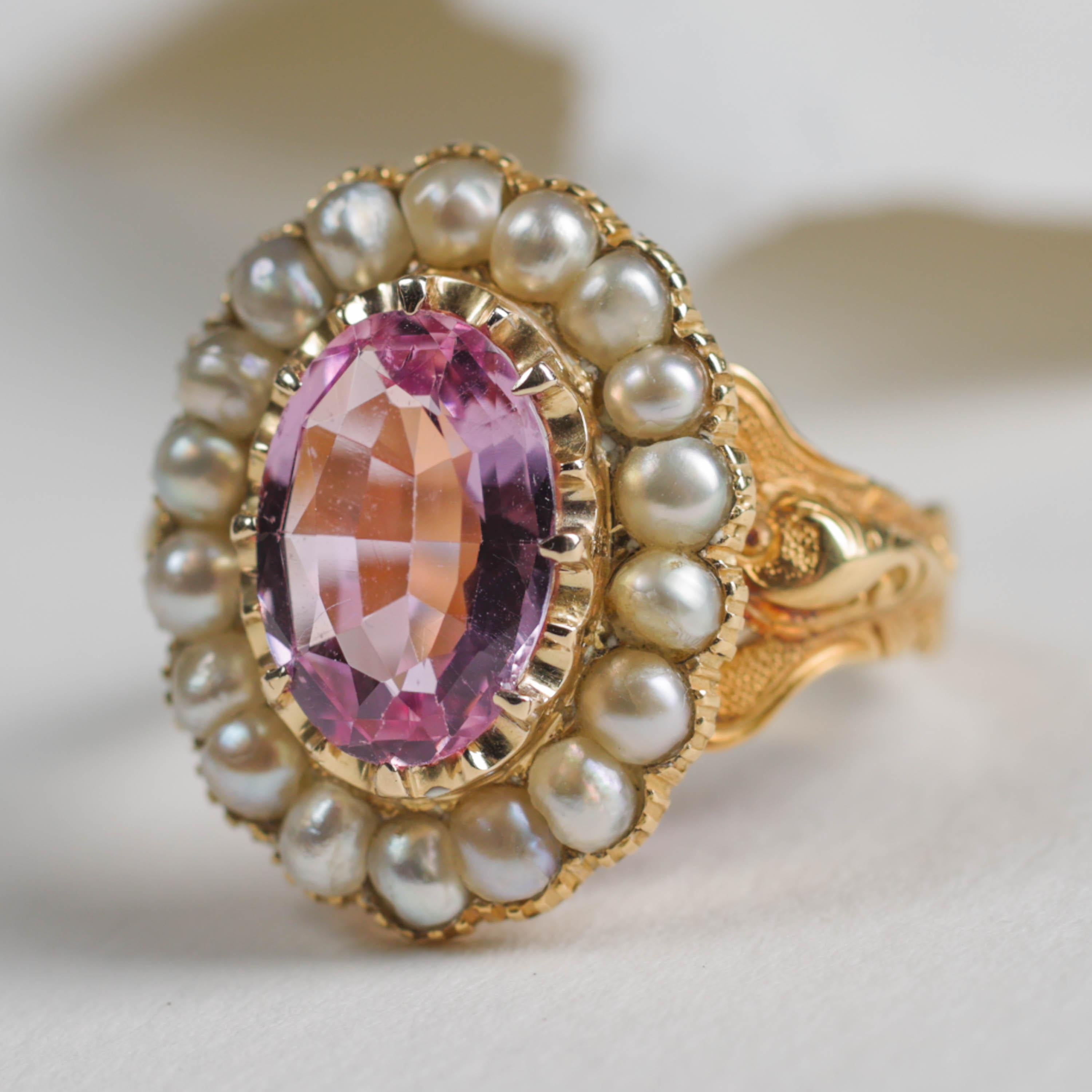 An unapologetically regal natural, untreated pink topaz gemstone is surrounded by a halo of natural uncultured saltwater pearls in this magnificently rare and beautiful unisex ring from the second half of the 19th century. 

Dating to 1843 and made