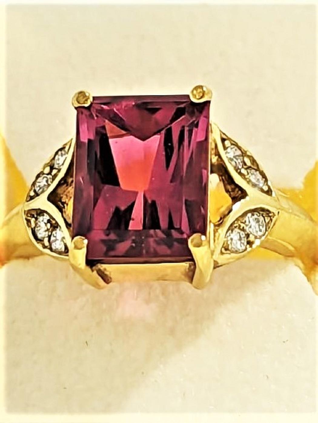 /Crafted from Afghanistan rough material, this pink tourmaline sits in an 18K yellow gold mounting (5.46grams) with flower motif on each side.  The Flowers are each set with two diamonds making the 4 stones weighing 0.11cts.  The diamonds are graded