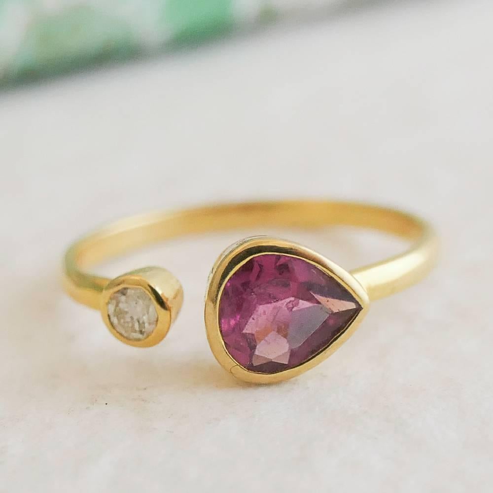 A 4x5 mm faceted pear shape  pink tormaline is set in 18kt gold. 
There is a small 3mm rose cut champagne diamond  on the other end. . 
Band is 1.6mm in width. 

This is a one of a kind piece and cannot be resized.  

Size 6.5