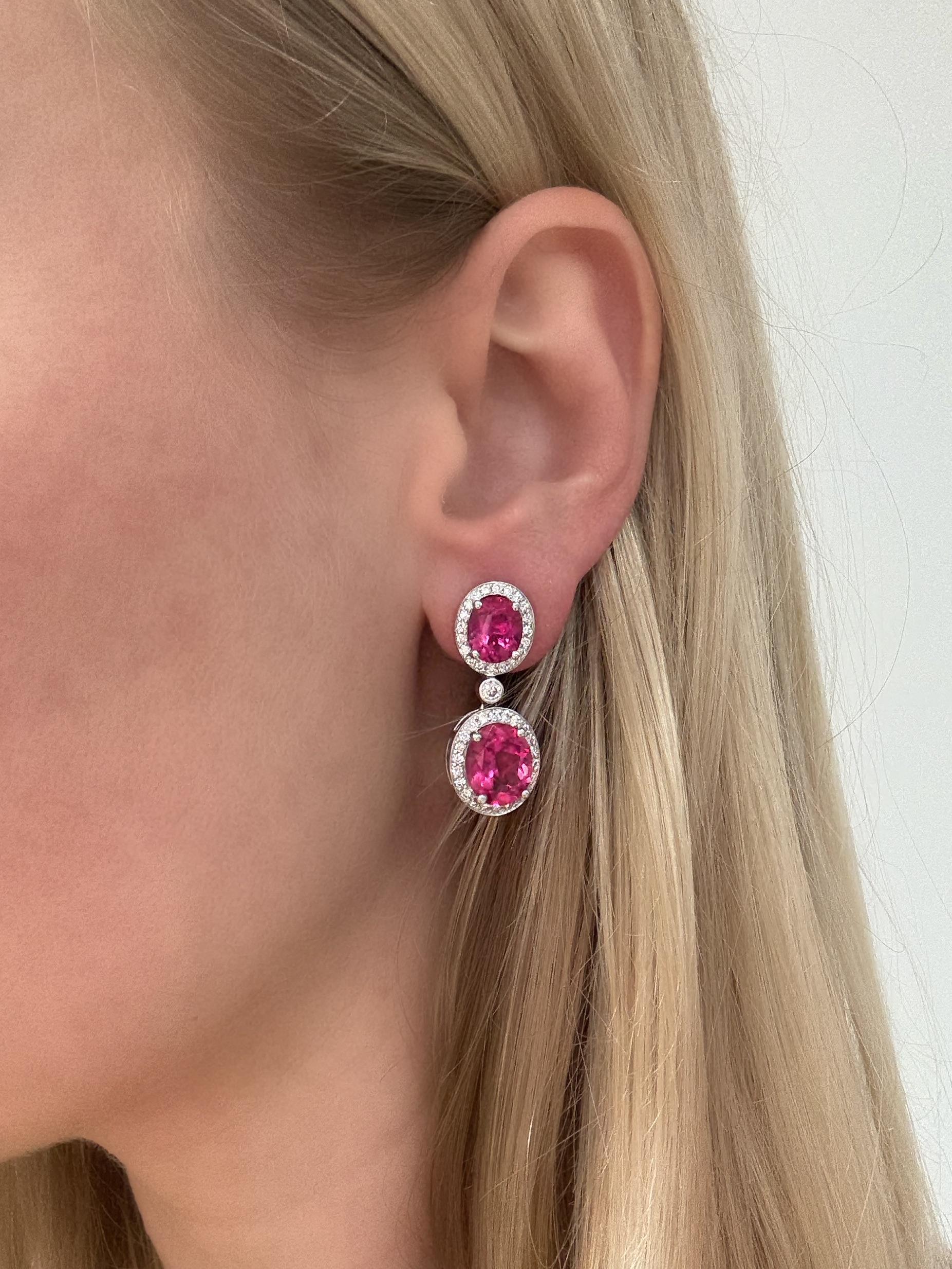Estos pendientes brillantes y coloridos contienen cuatro óvalos de color rosa  Turmalinas con un peso total aproximado de 11,00 quilates, rodeadas de diamantes redondos de talla brillante con un peso total aproximado de 2,25 quilates. Montados en