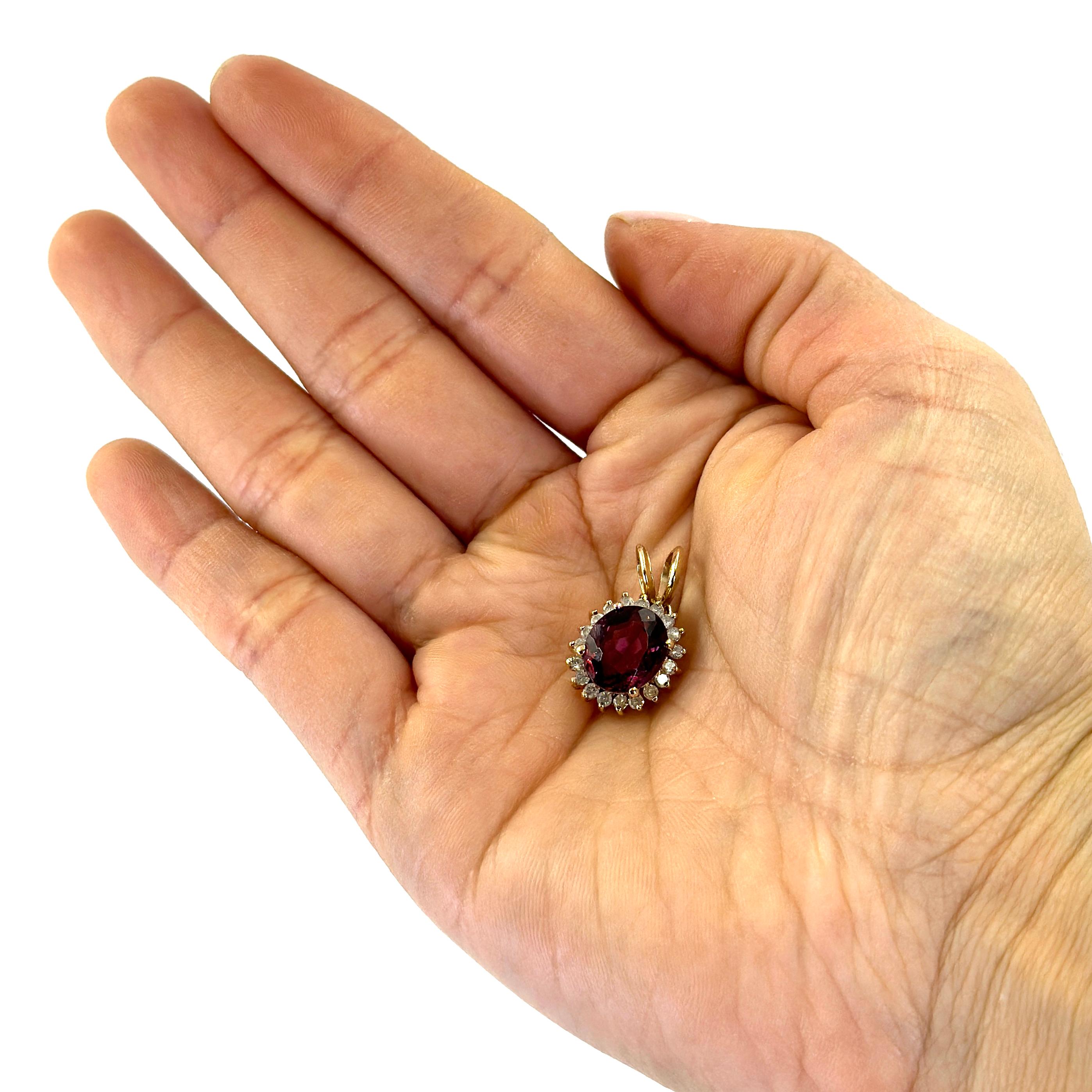 Pendentif en or jaune 14 carats orné d'une tourmaline rose de taille ovale mesurant 10,25 mm x 8,8 mm et pesant environ 3 carats, entourée de 19 diamants ronds de pureté I et de couleur J totalisant environ 0,19 carats. Longueur de 0,75 pouce avec