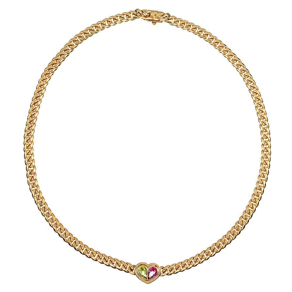 Made of 18 karat yellow gold, the curb chain is interrupted by a heart shape fashioned of pear-shaped pink tourmaline and peridot. 16 inches long, with a substantial hand, and signed “Bvlgari” on the clasp.
