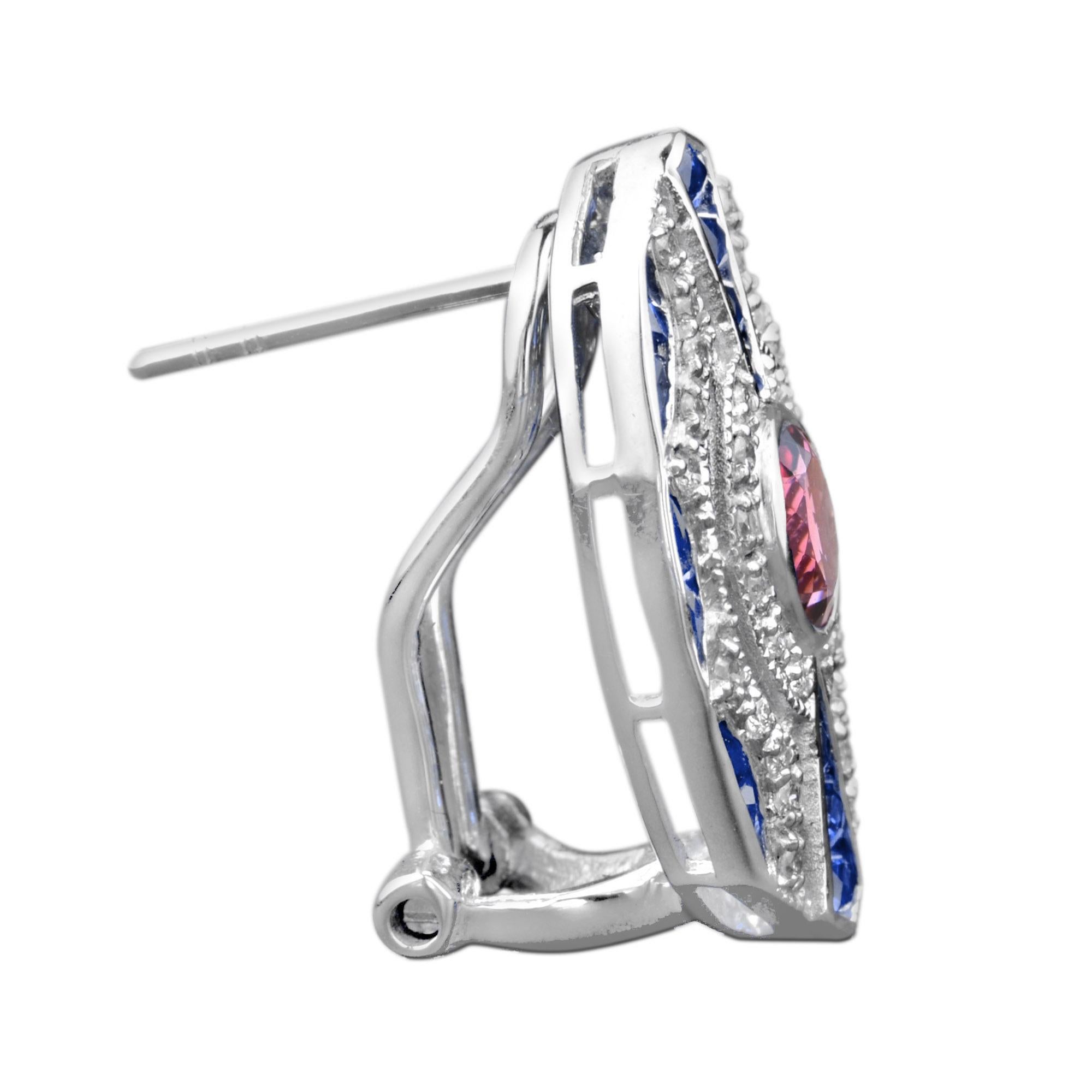 Ein rosafarbener Turmalin mit einem Gewicht von ca. 1,10 Karat pro Seite glitzert und leuchtet in der Mitte der geometrisch konstruierten Omega-Ohrringe im Art-déco-Stil. Der Edelstein ist von runden Diamanten und Saphiren im französischen Schliff