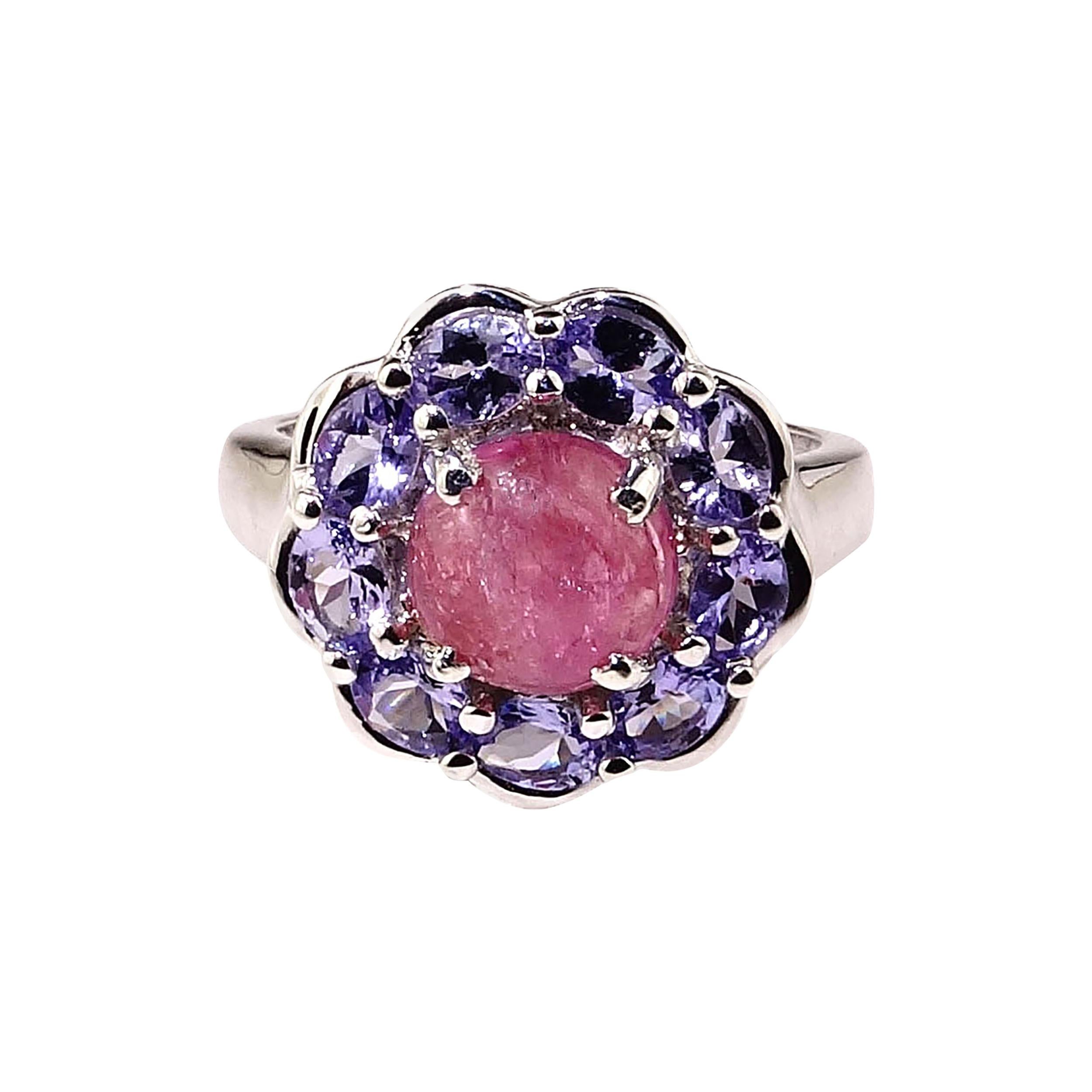 Elegant cocktail ring featuring a glowing translucent cabochon Pink Tourmaline surrounded with sparkling lavender Tanzanites.  The round Pink Tourmaline has all the typical inclusions of a translucent tourmaline many of which actually help reflect