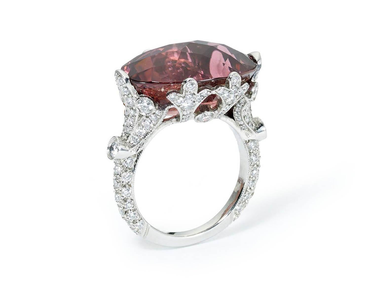 A tourmaline and diamond ring, set with a pineapple-cut pink tourmaline, weighing 13.95ct, with diamond set shank, fleur-de-lis settings and trefoil shoulders, with an estimated total diamond weight of 1.26ct, mounted in platinum.

UK size L / USA 5
