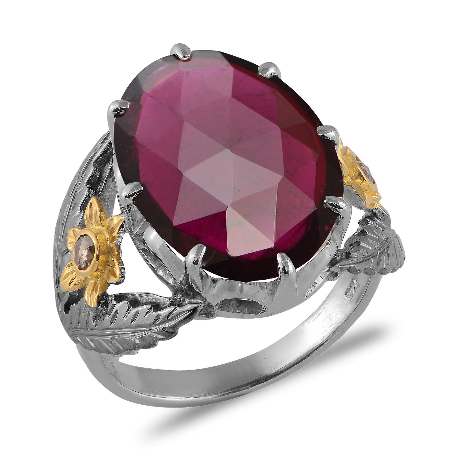 

A lovely one-of-a-kind pink tourmaline cocktail ring. This ring features a central pink tourmaline, set in hand-engraved oxidized sterling silver, and flanked by two full cut diamonds which are set in 18kt gold hand-engraved flowers. This ring has