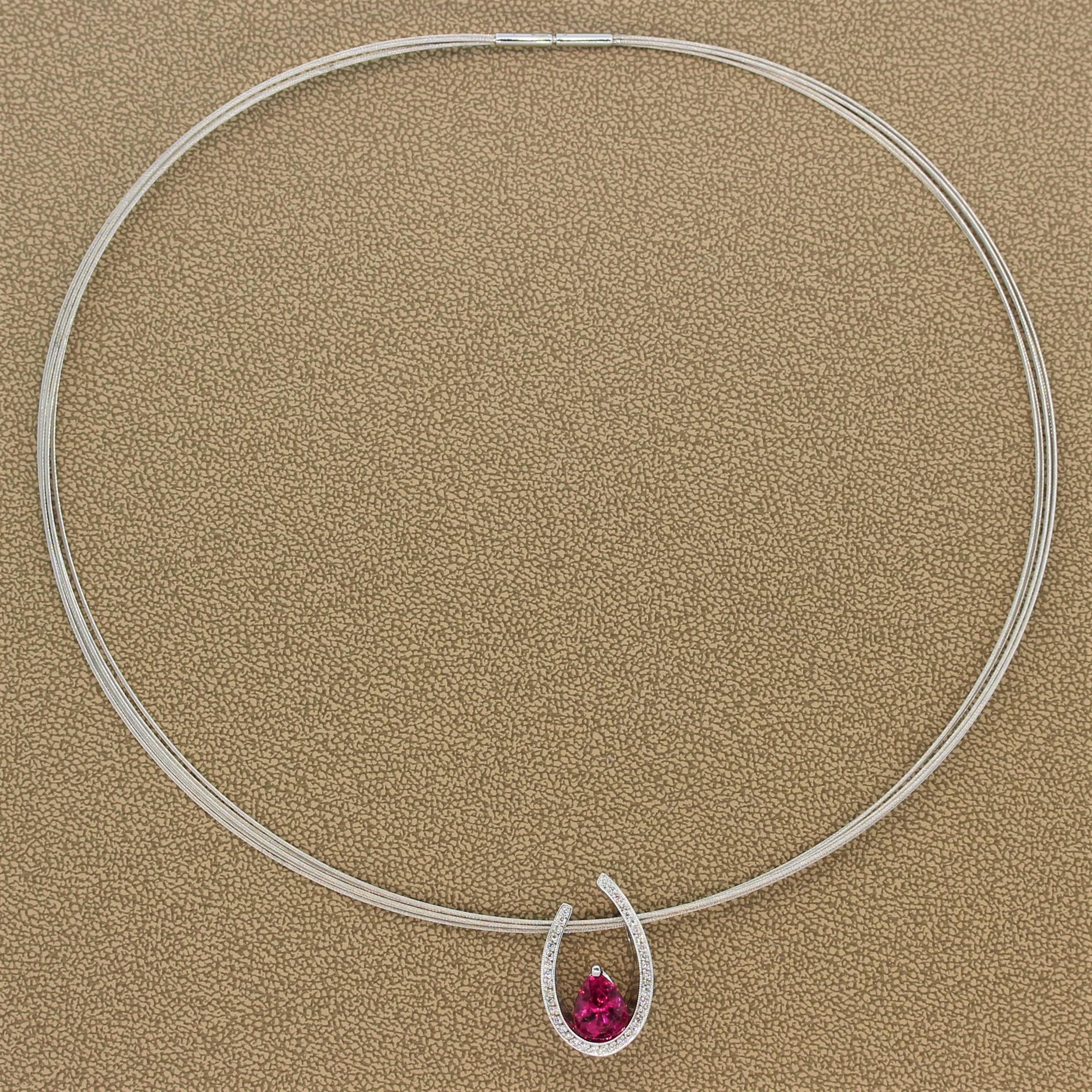 A beautiful pendant featuring a 2.12 carat vivid pink tourmaline. The feminine gemstone sits gracefully at the bottom of a horseshoe shaped 14K white gold slide setting studded by 0.21 carats of round cut diamonds with a milgrain design along the