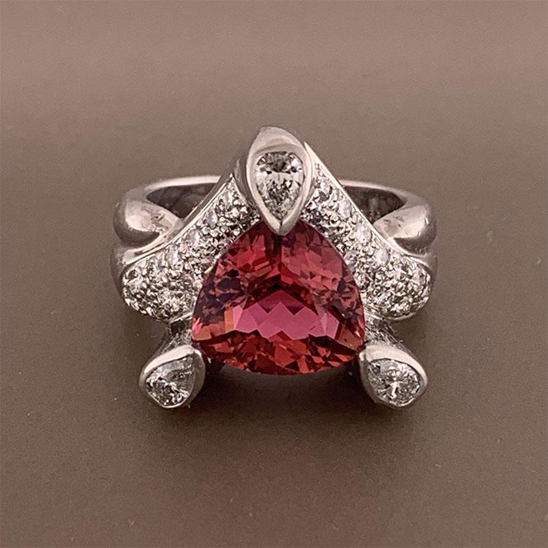 A lovely platinum made ring featuring a 3.69 carat trillion cut pink tourmaline. The luscious gemstone is accented by 0.97 carats of round cut diamonds and three pear shaped diamonds set atop the 3 prongs. A great addition to any collection. 


Ring