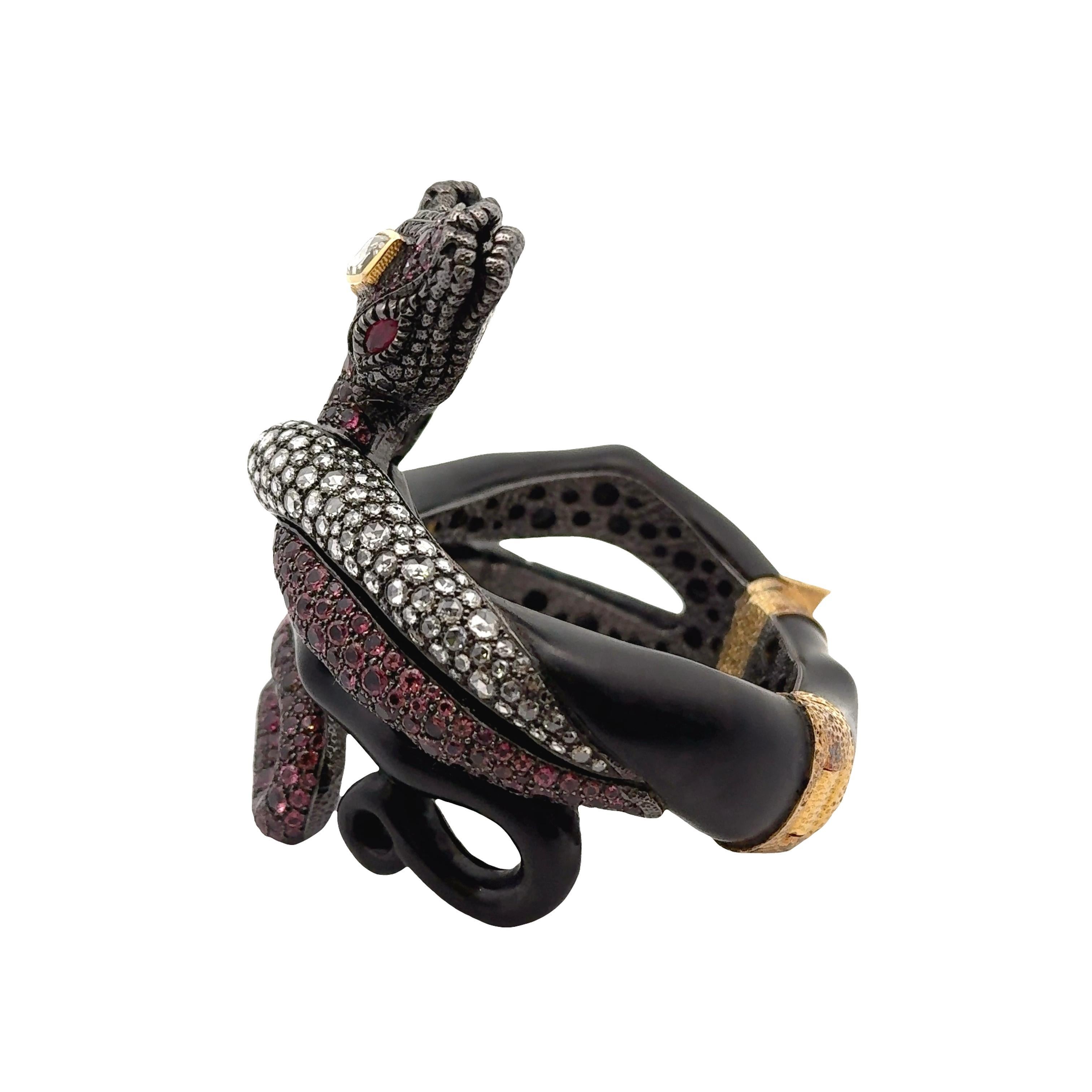Le design présente deux motifs de serpent entrelacés, ornés de tourmalines roses rondes totalisant 25,20 carats. Des diamants blancs taillés en rose, d'un poids de 11,18 carats, rehaussent le design. D'autres embellissements comprennent des pierres