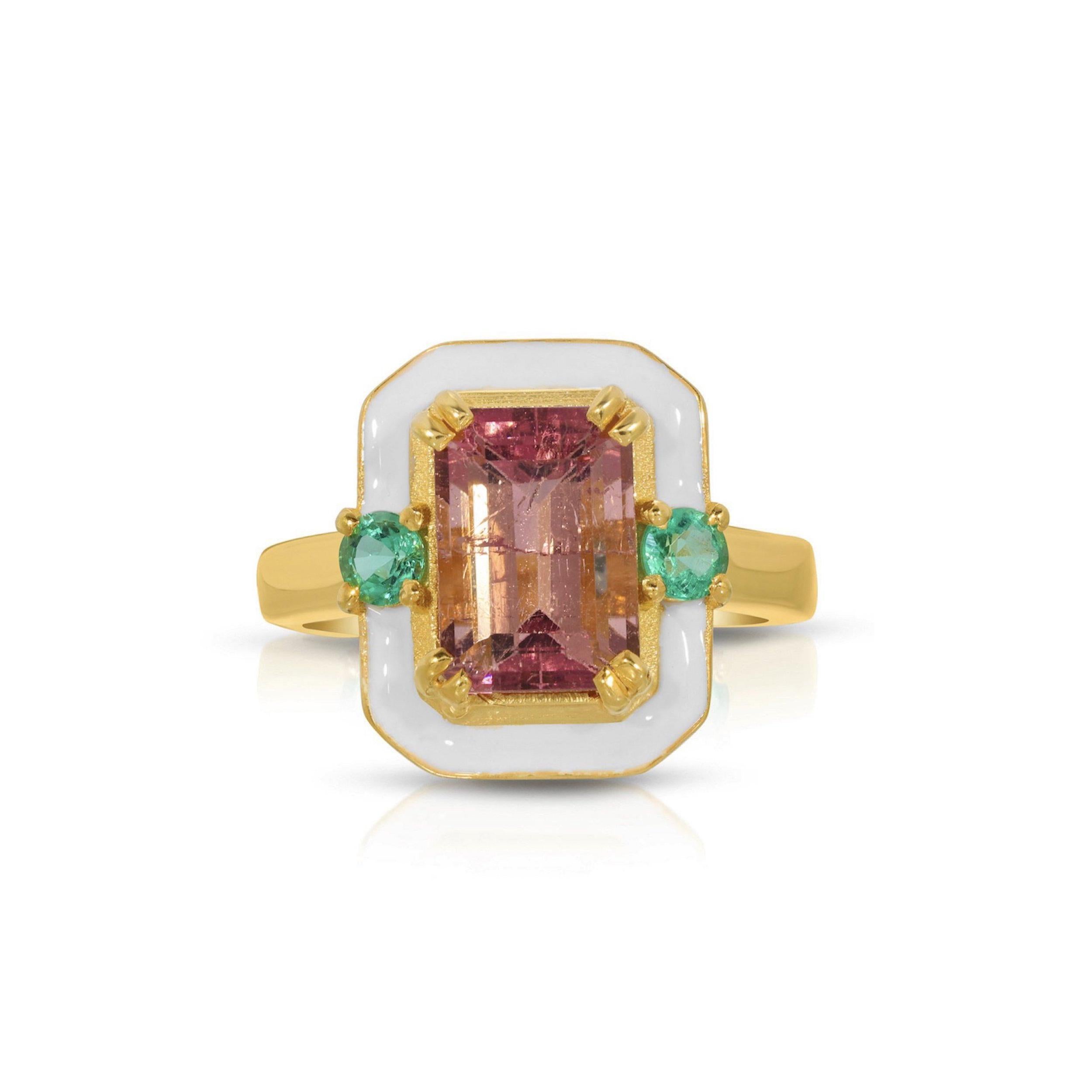 A gorgeous cocktail ring of modern design with a mix of gemstones and enamel. This ring features a beautiful emerald cut Pink Tourmaline center stone set with two round cut fiery Emeralds and glossy white enamel. This ring is set in stylish 22 Karat