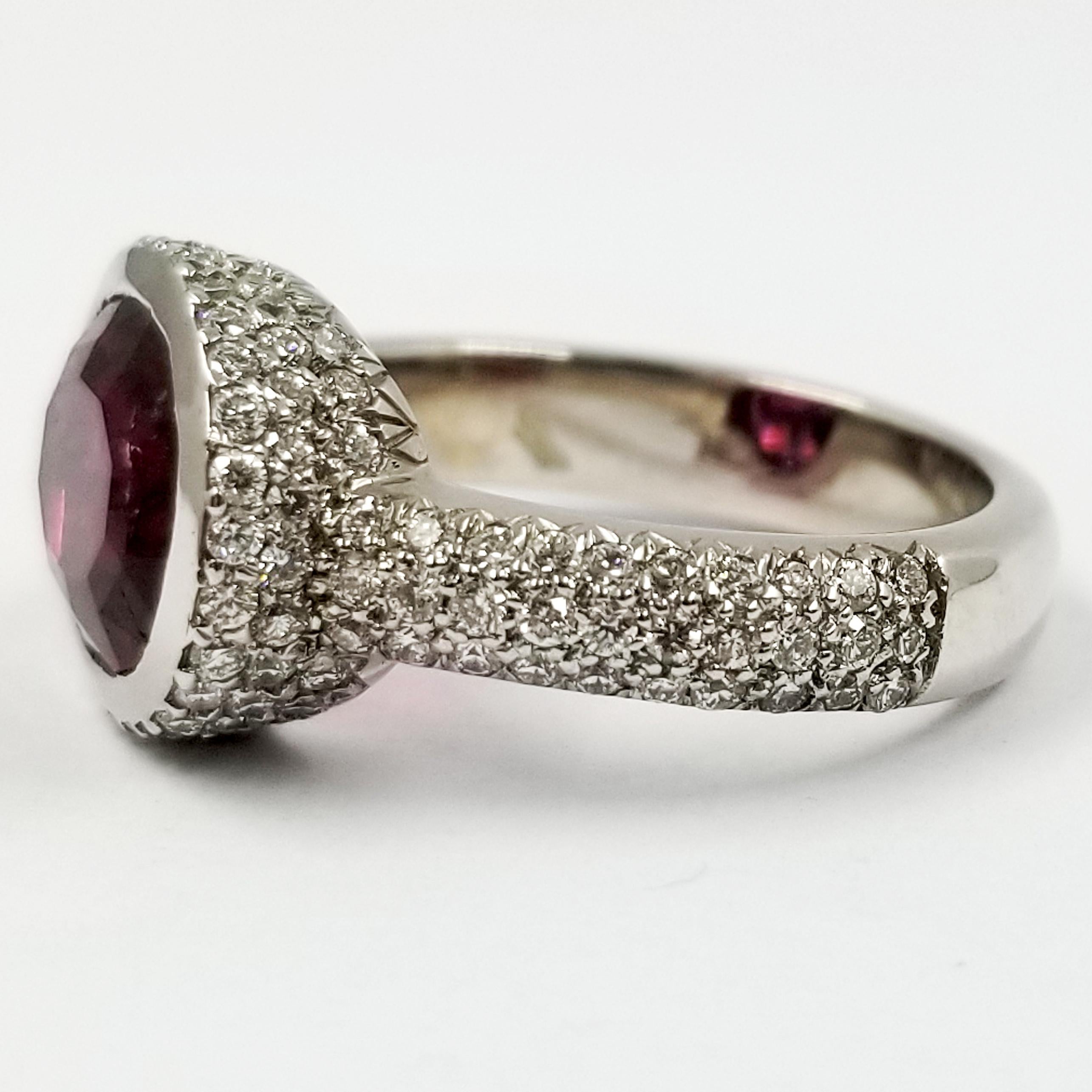 18 Karat White Gold Ring Featuring A Bezel Set Oval Cut Pink Tourmaline Weighing Exactly 3.05 Carats. The Tourmaline Center Stone Has Eye Visible Natural Inclusions. It Is Surrounded By 128 Pave Set Round Diamonds Of VS Clarity & G Color Totaling