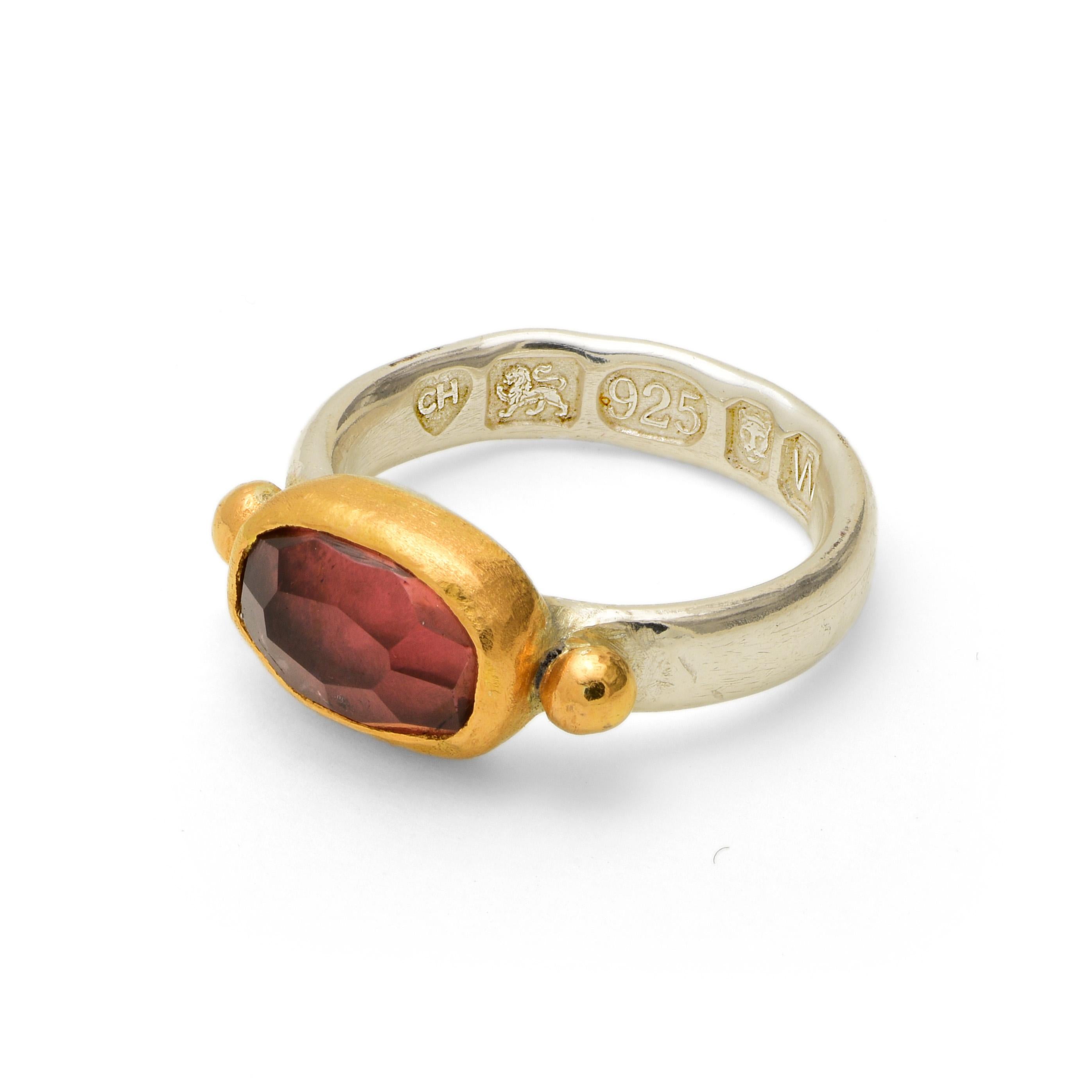A ring with 22 karat gold balls either side of this lovely faceted pink tourmaline stone. The stone's setting is also 22 karat gold and the band is made from thick sterling silver. There is a large, deep British hallmark on the inside of the