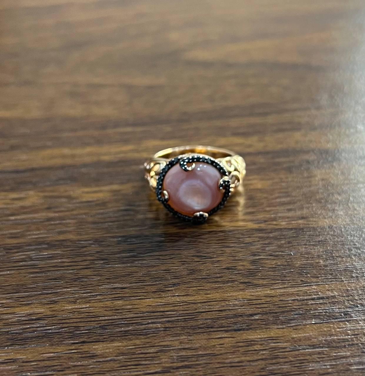 A striking Mother of Pearl and Black Diamond Statement Ring, featuring a captivating pink Mother of Pearl set in 14k Rose Gold, accentuated by 0.25ct Black Diamonds.