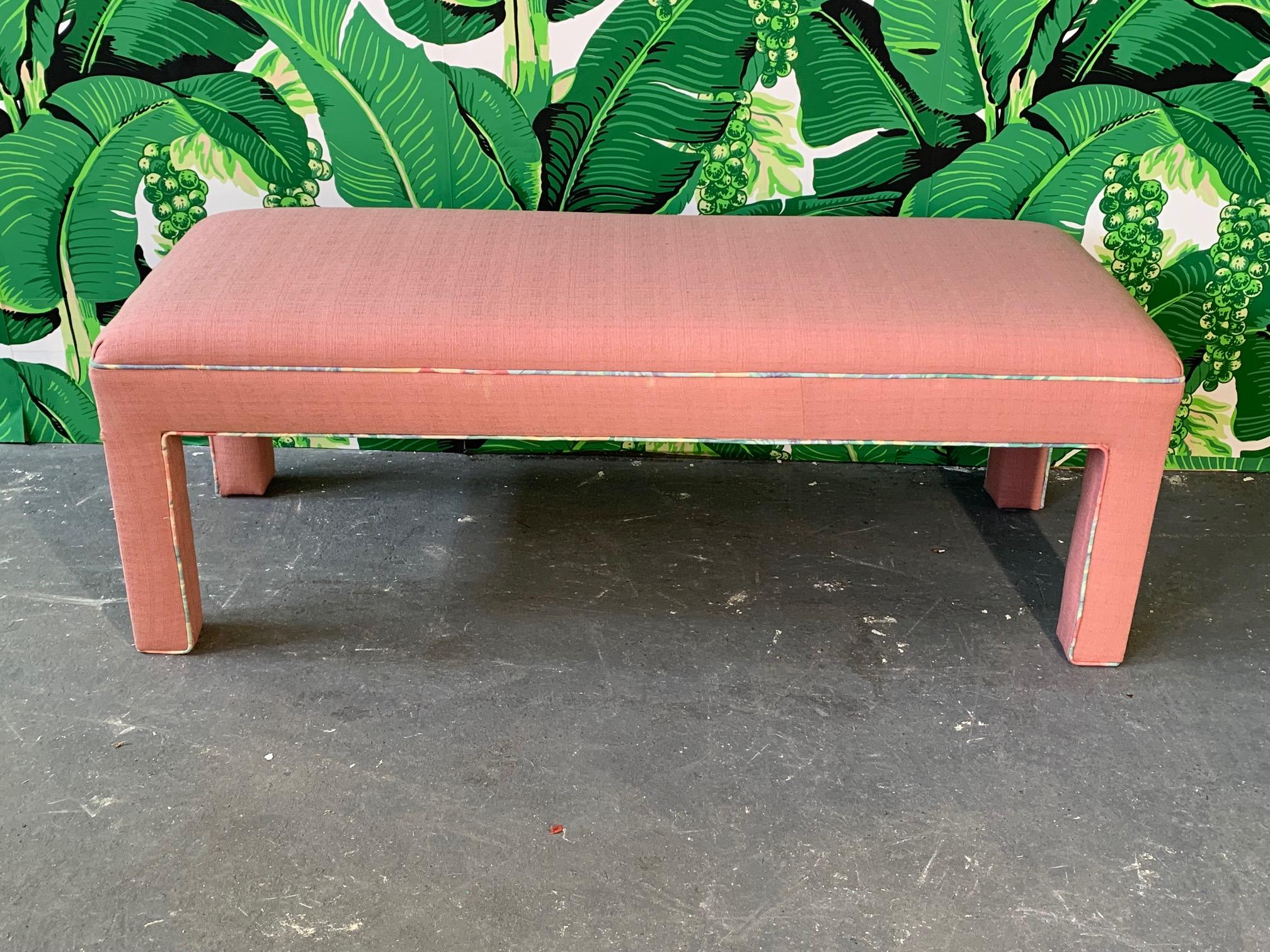 Upholstered bench or ottoman in true 1980s style. Pink with pastel tropical piping. Very good condition.