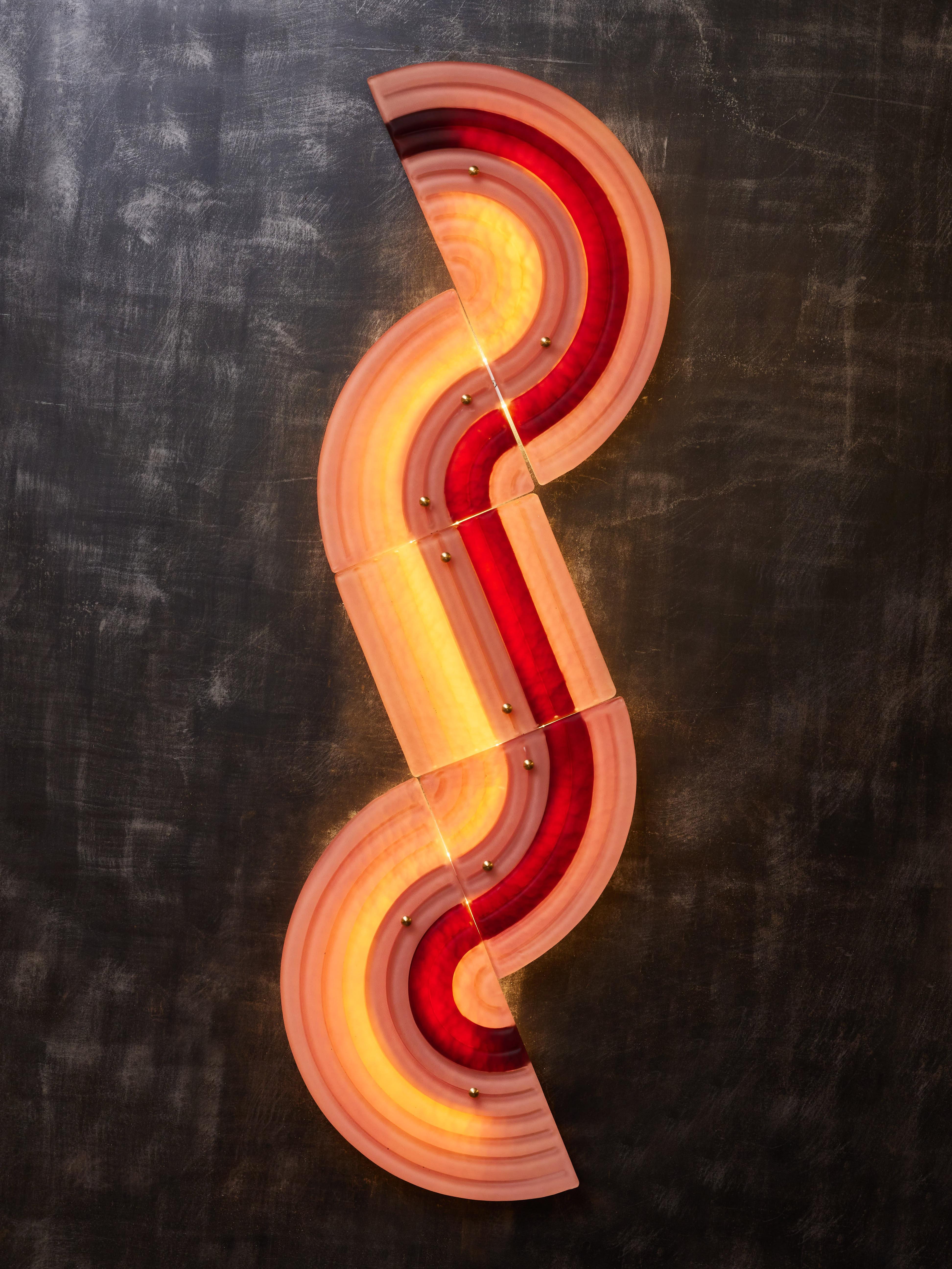 Wavy wall sconces made of a metal structure with LED lighting, covered with five Murano glass coloured panels. These sconces can be attached in any direction and assembled to create larger pieces.