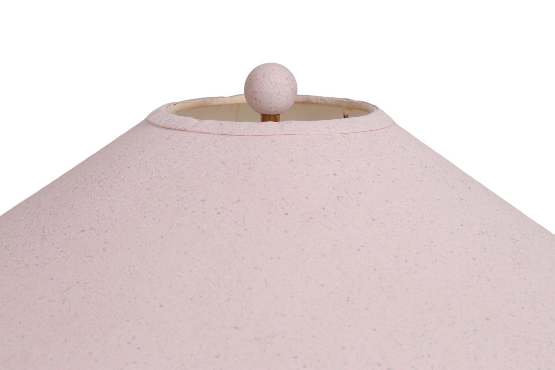 Une lampe de table en fer forgé personnalisée en rose avec un abat-jour en forme de coolie. Cinq rubans de fer roses enroulés entourent la colonne centrale, attachés au sommet et à la base ronde biseautée par des nœuds décoratifs à volutes. Une