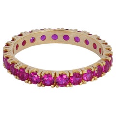 Pinkish red gemstone 14k gold eternity ring band.