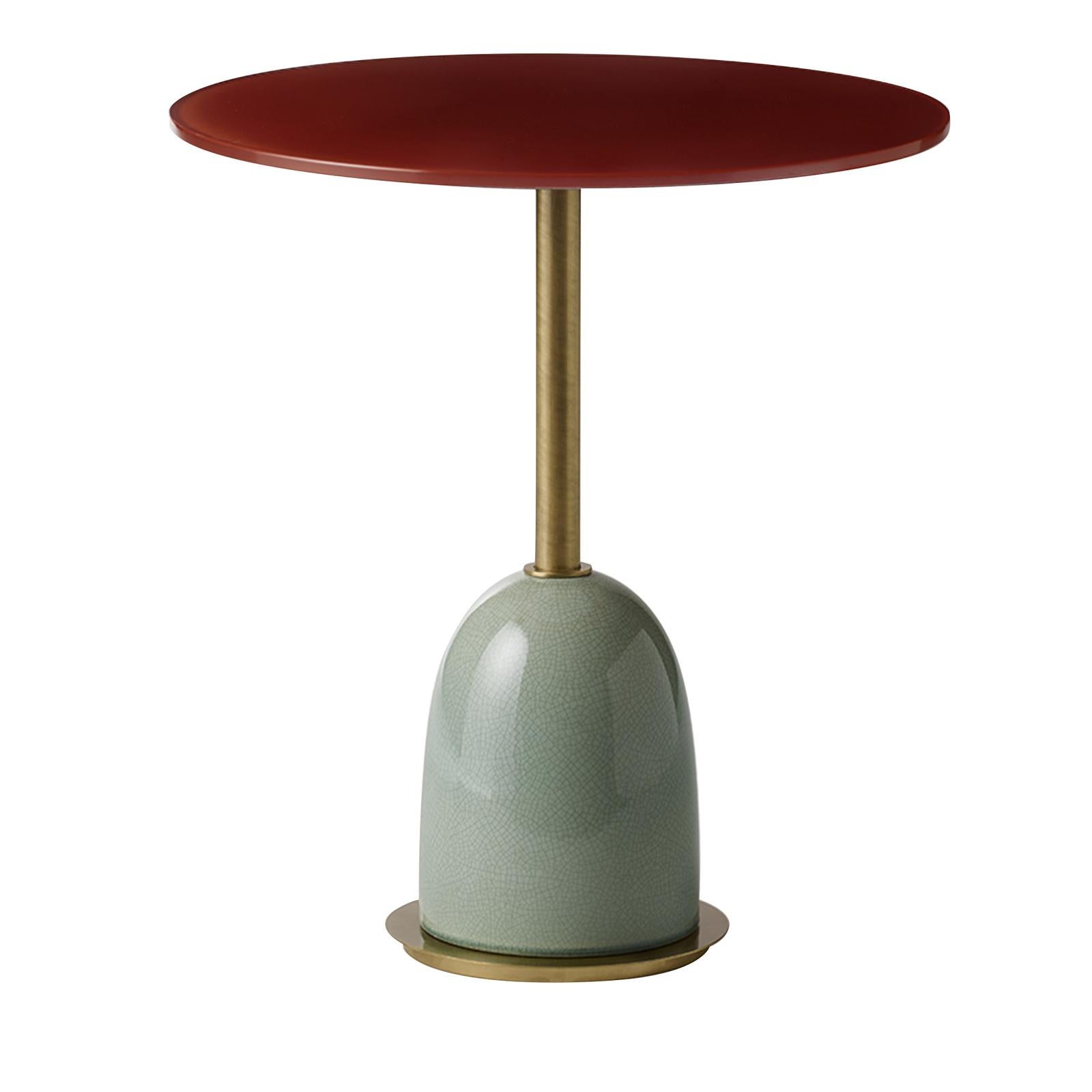 This table has a brass structure and an enameled ceramic base, supporting a back-colored glass top. In this case the turquoise base, with a stunning crackled finish, is a striking complements to the red-colored top and the gold tones of the brass.