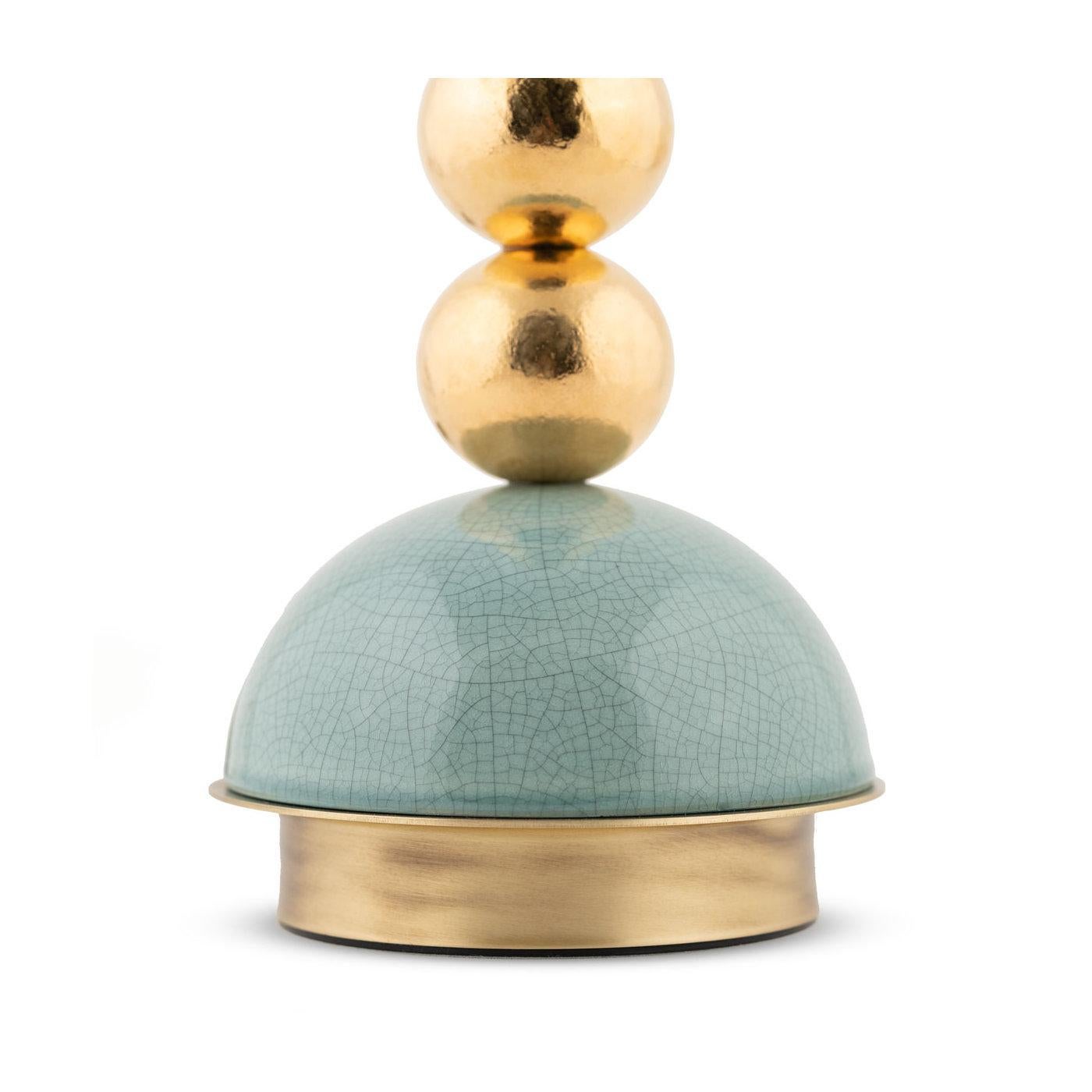 An elegant interplay of lines and volumes, this sculptural table lamp will make a stylish addition to any modern decor. The piece is composed of four, golden-hued ceramic spheres composing the main body, all resting on a turquoise-glazed ceramic