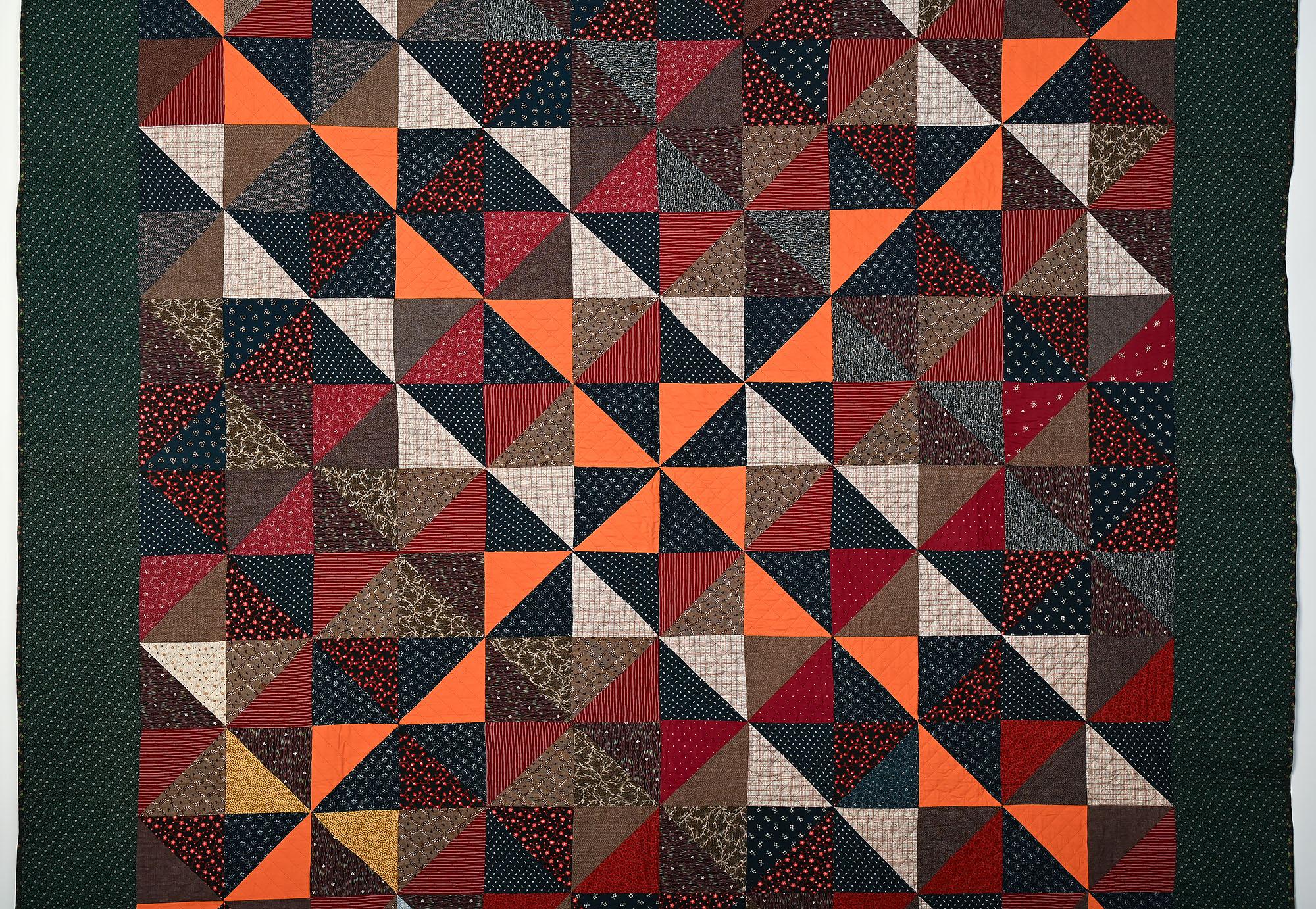 Der interessante Einsatz von Farben macht aus diesem Quilt viel mehr als einen gewöhnlichen Pinwheels-Quilt. Alle Stoffe sind bedruckt, mit Ausnahme der einfarbigen orangefarbenen Dreiecke, die ein Kreuz bilden. Die Unterlage ist ein weiterer Druck,