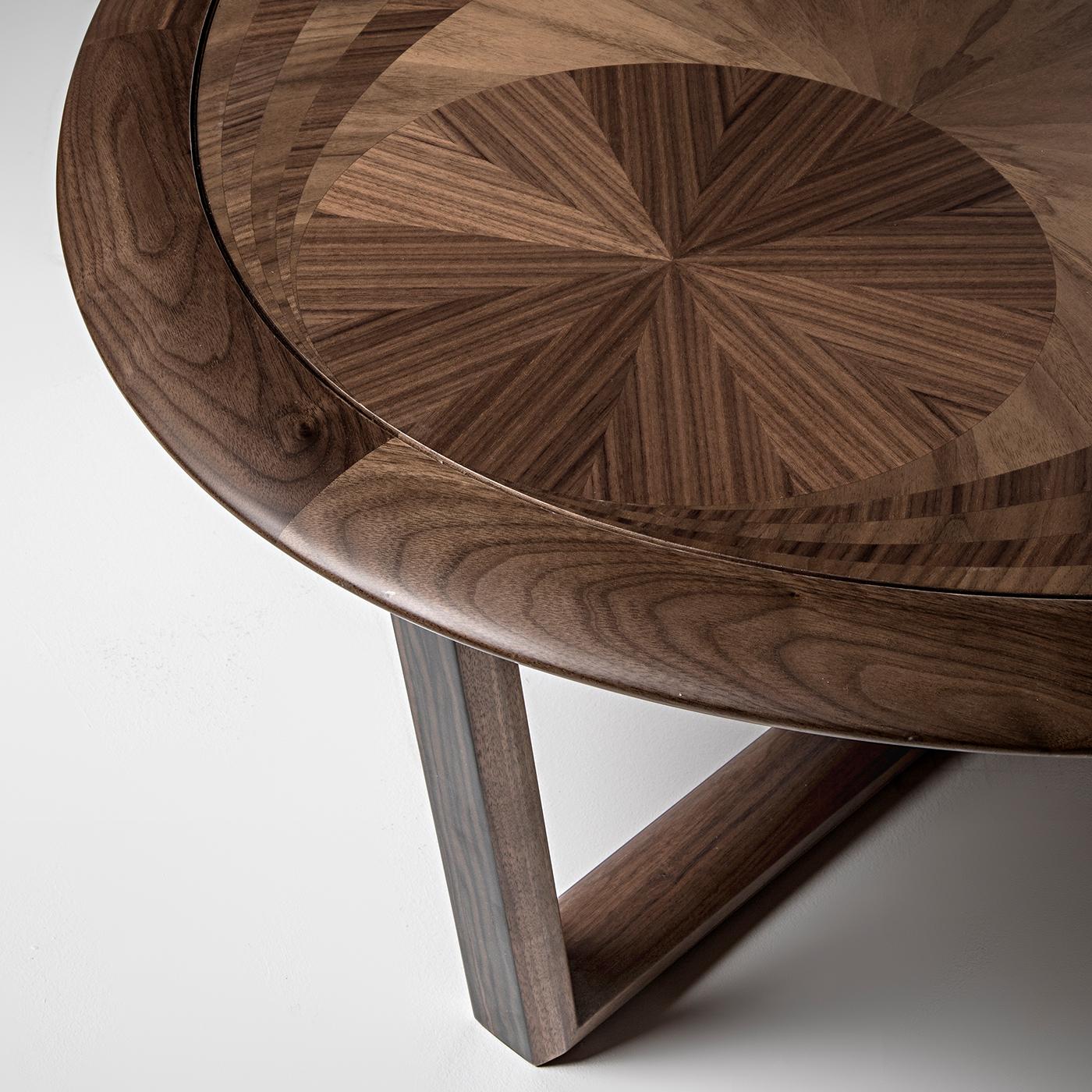 Le charme inégalé de cette table basse provient de l'interaction entre des bois précieux tels que le noyer Canaletto et l'ébène. Deux gracieux éléments angulaires se croisent à la base, créant un support dynamique pour le plateau ovale, dont le