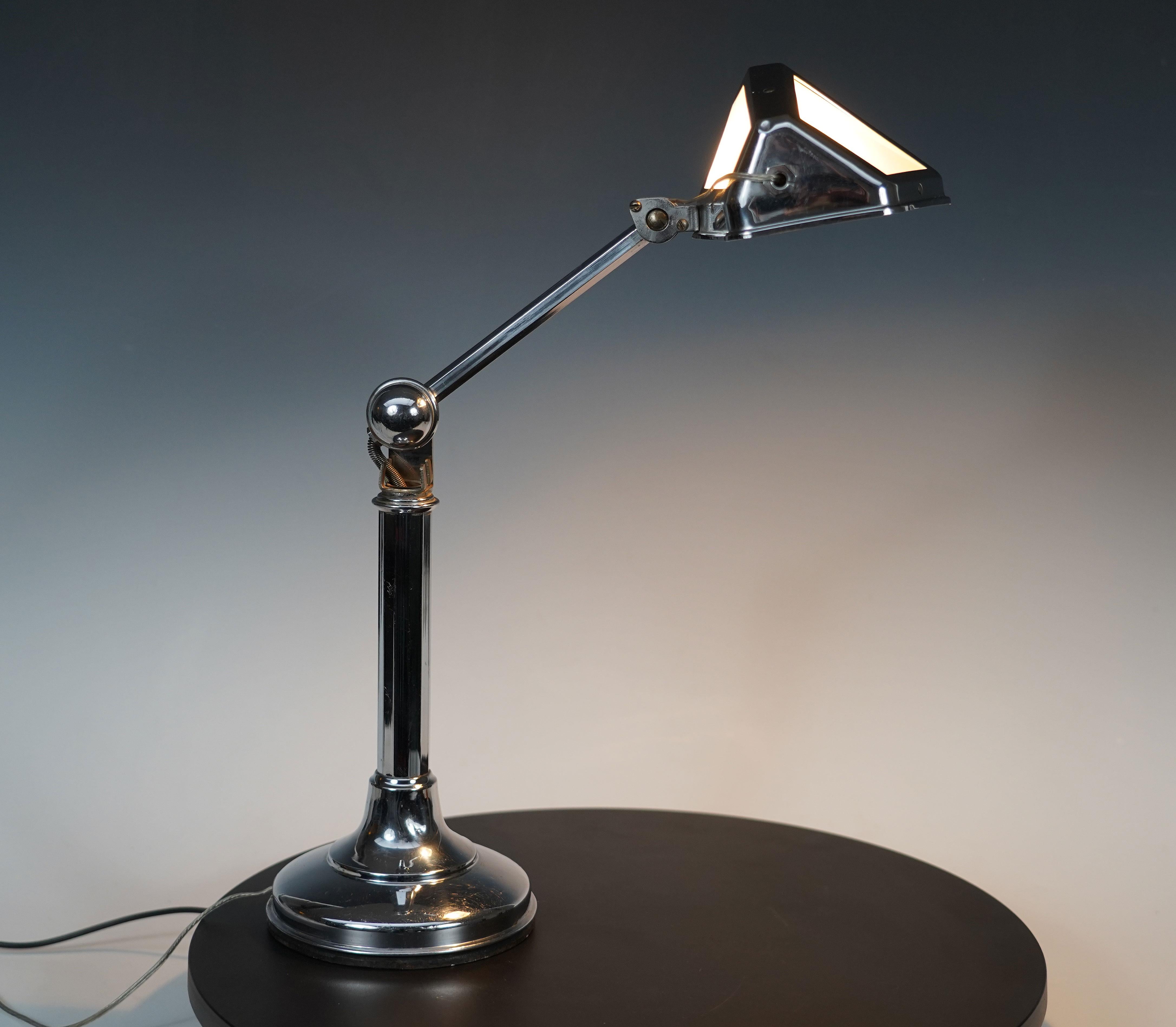 Chromed brass desk lamp. Composed of a faceted shaft resting on a circular base, it has the particularity of having a tilting and adjustable arm, ending in a shade with sandblasted glass windows.

Pirouett Lamp :
The Pirouett lamp is a range of