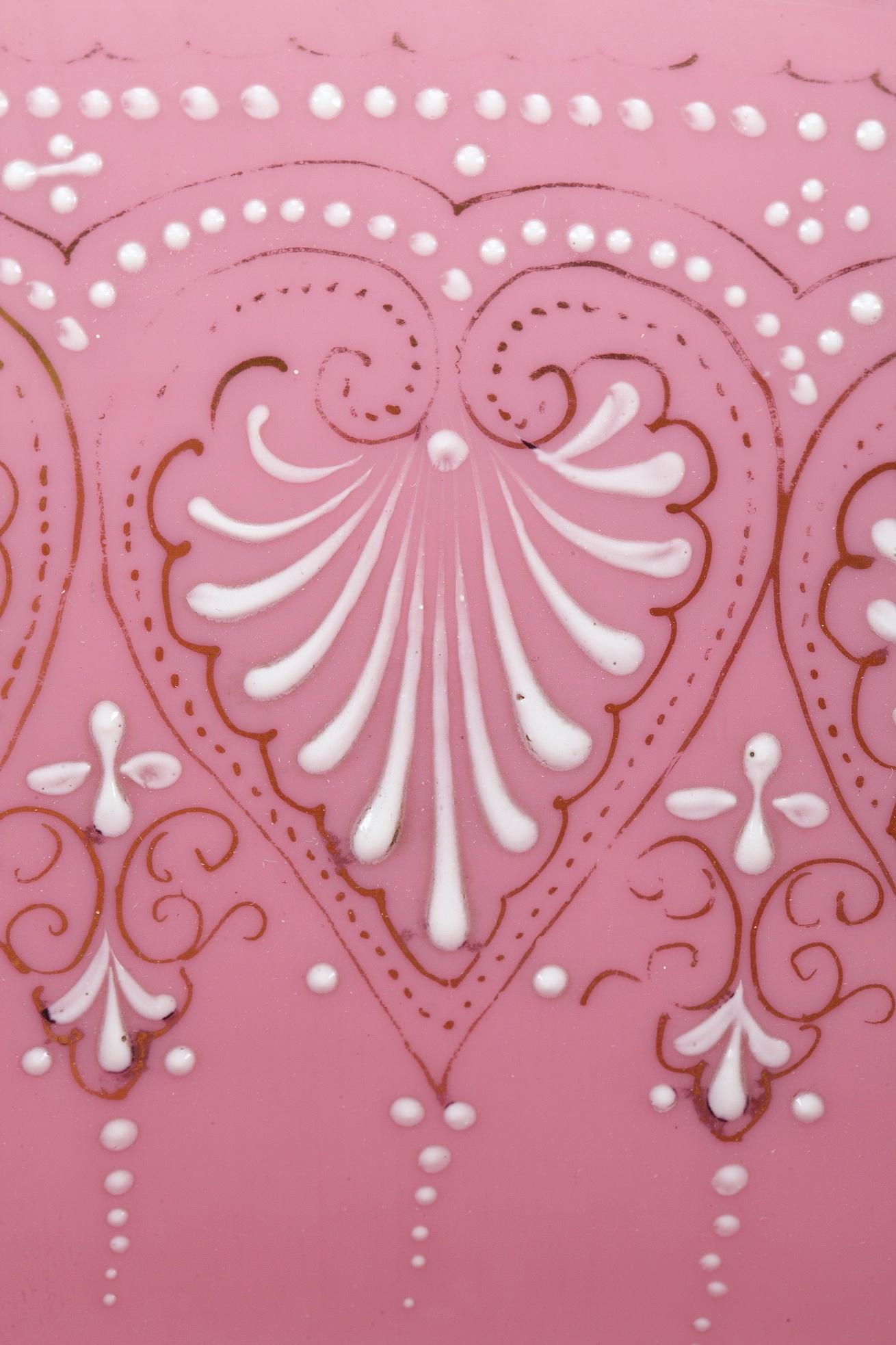 Grand pichet en opaline rose et son bassin, à décor émaillé blanc et or de palmettes, petites perles et motifs floraux. De larges bandes d'or soulignent le bord, l'anse et la base de cette aiguière ainsi que le bord du bassin. L'ensemble repose sur
