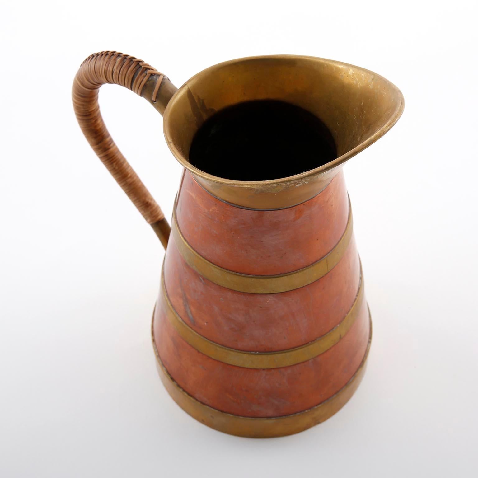 A pitcher made of copper, brass, and cane manufactured in midcentury, circa 1960 (late 1950s or early 1960s).
An authentic handmade piece in very good original condition with nice patina on brass, copper, and cane.