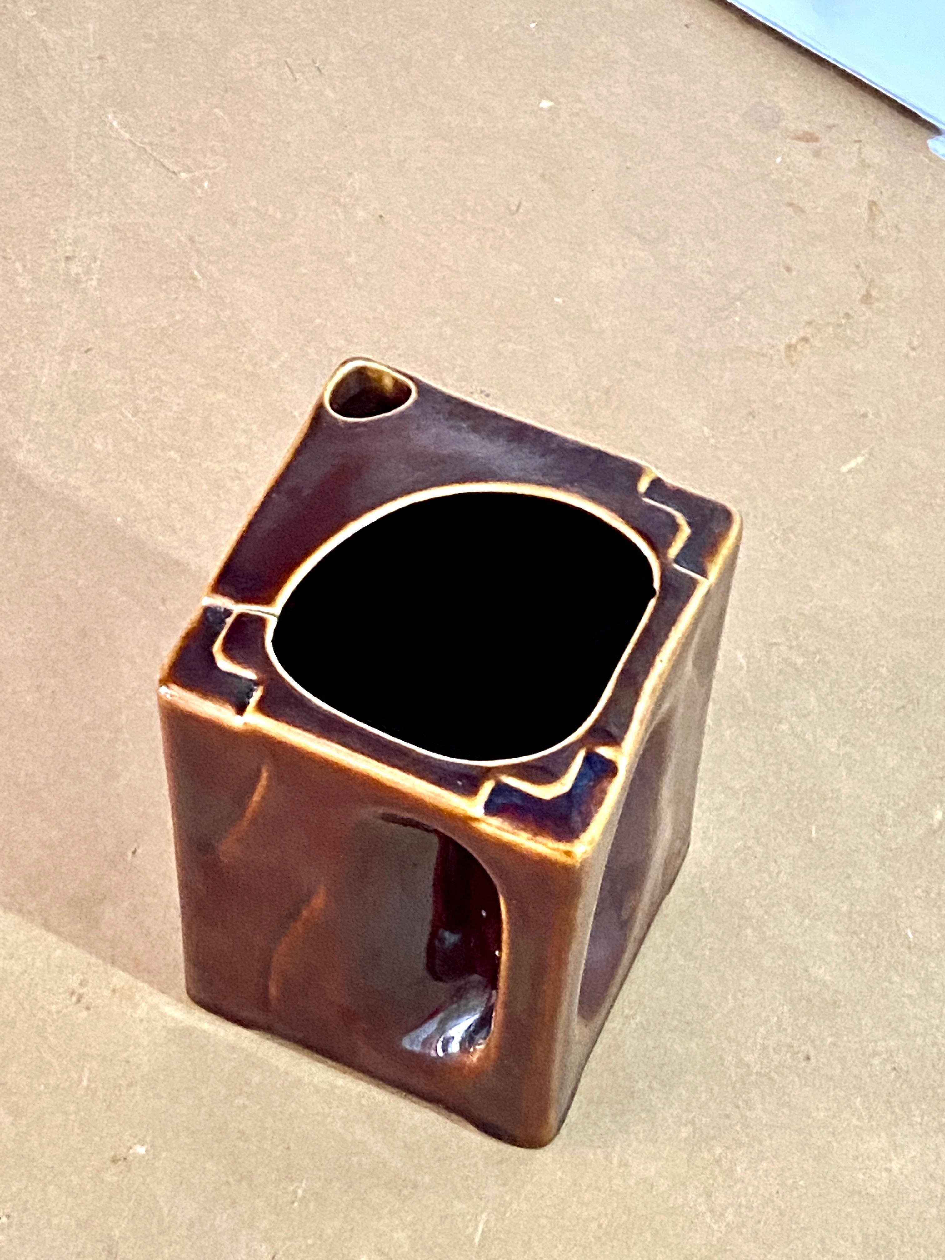 This Pitchet is made of ceramic, with a very original shape. The handle, or the ance, is integrated into the body of the jug which therefore has a rectangular shape. It is brown in color, and was created in the 1960s in Vallauris, France.