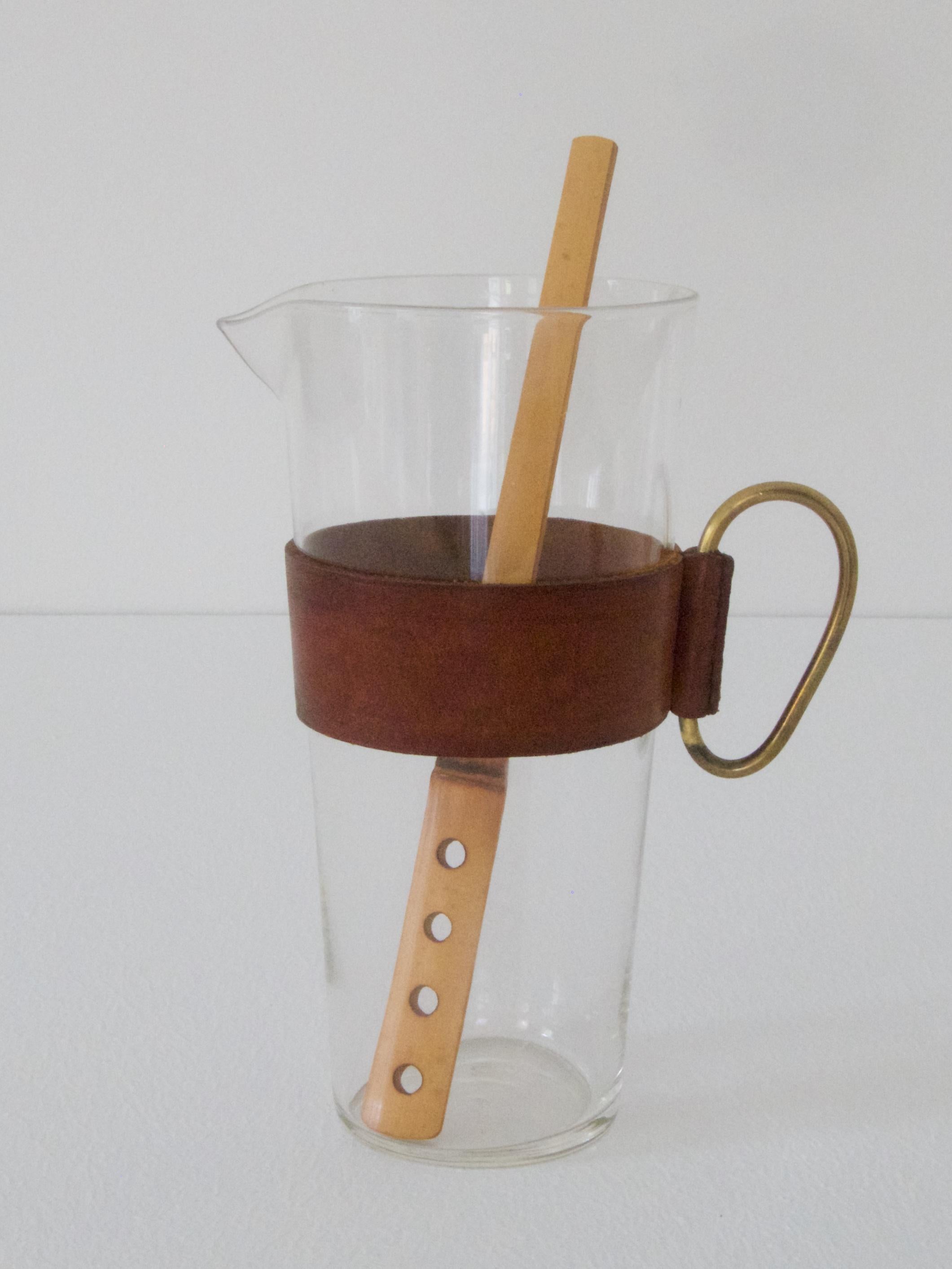 Pitcher with a bamboo muddler No. 3749
by Carl Auböck
hand blown glass, leather sleeves with a brass handle, bamboo muddler

Ø 8,9 cm, H 17,5 cm
muddler 21,3 cm

Good condition - nice patinated leather.
 
Lit.: die kataloge der werkstätte