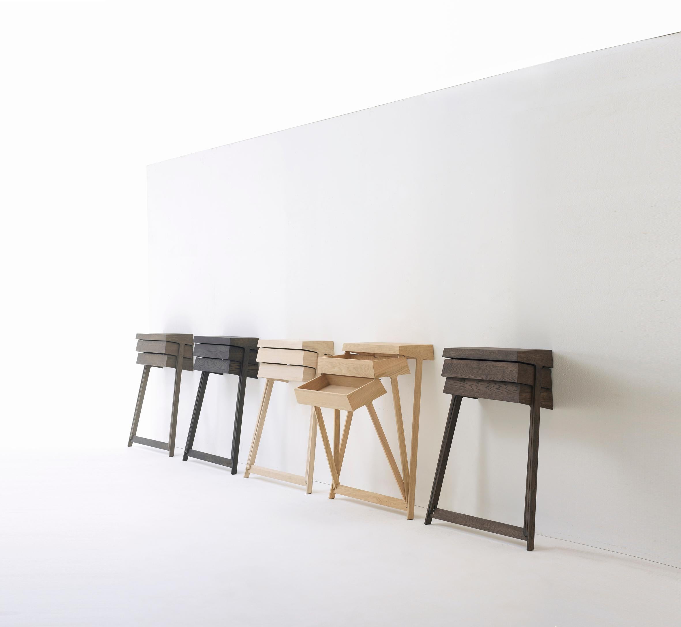 Pivot est une armoire en bois massif qui repose sur des pieds hauts et comporte deux tiroirs. L'aspect innovant de ce meuble réside dans le fait que les tiroirs peuvent s'articuler, ce qui permet d'ouvrir les deux tiroirs en même temps, ce qui est