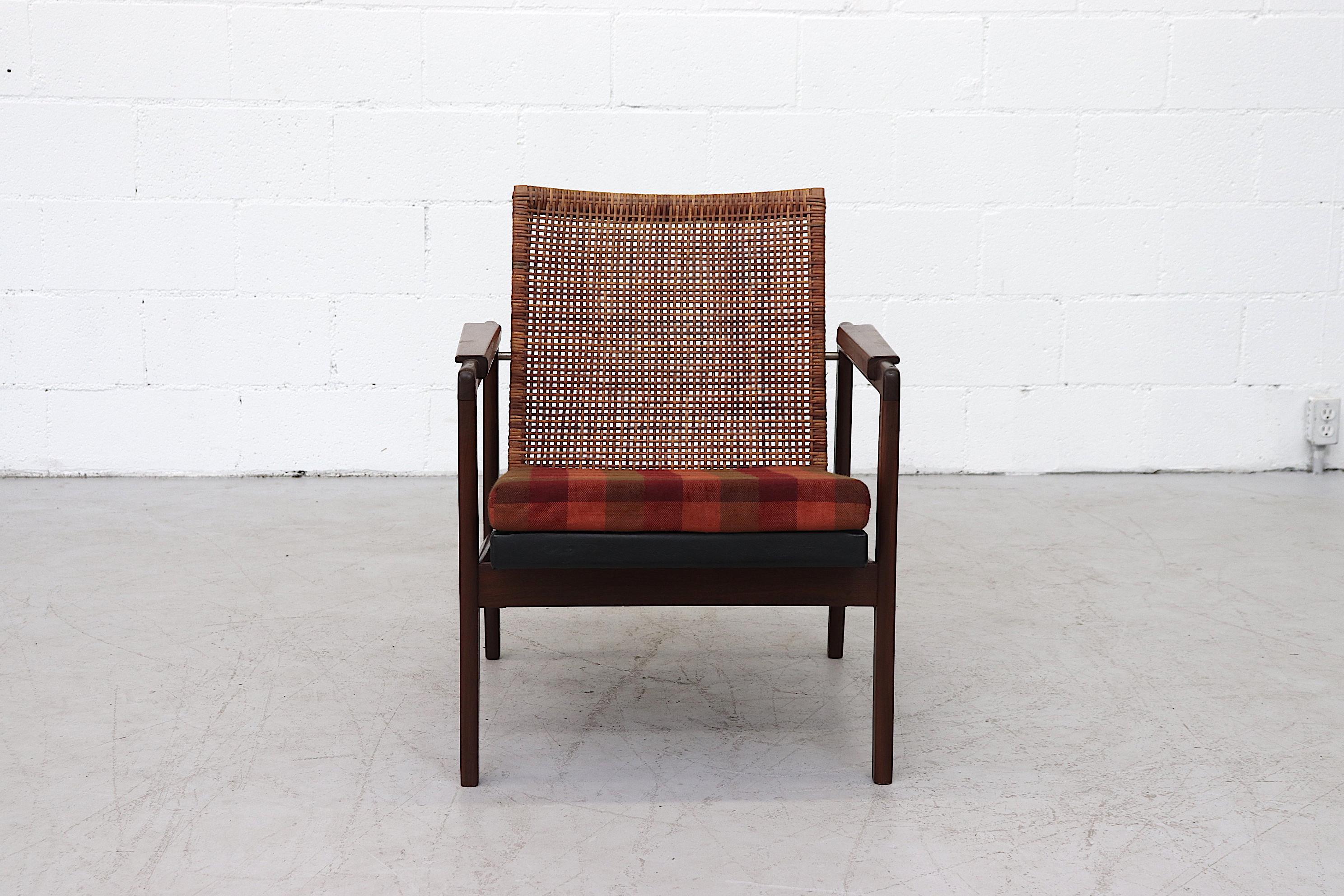 Amazing teak and rattan Muntendam lounge chair with original plaid cushion. Some breakage to the rattan (pictured), and some fraying to cushion fabric in original condition with visible wear consistent with its age and use.