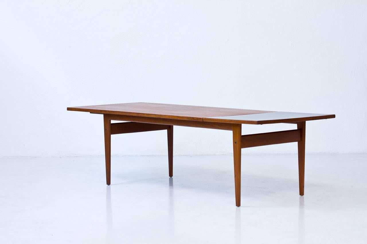 PJ 56B coffee table designed by Grete Jalk for P.Jeppesen in Denmark during the 1960s. Made of teak with a drop-leaf extension featuring a black formica surface.