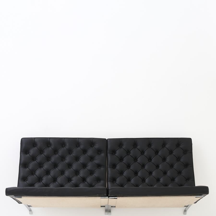 PK 26 - Wall-mounted sofa with two modules of spring steel and deep-stitched cushions in black leather. Maker Frits Hansen.