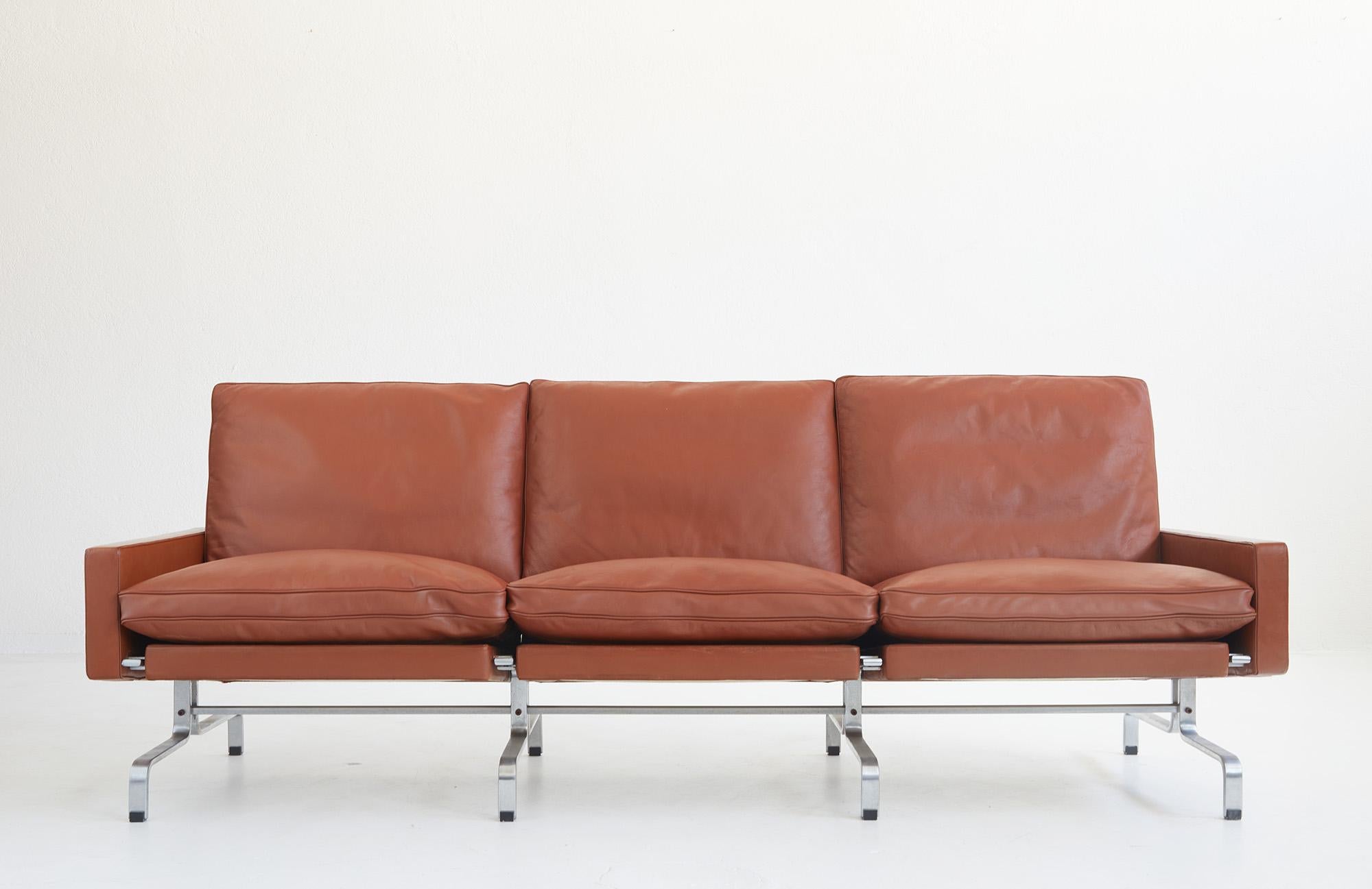 Iconic PK31 three-seater leather sofa by Poul Kjærholm, EKC Denmark 1958.

This sofa is from the first edition produced by E.Kold Christensen until Fritz Hansen takes over the production in 1970.

The heavy and high quality brushed steel structure