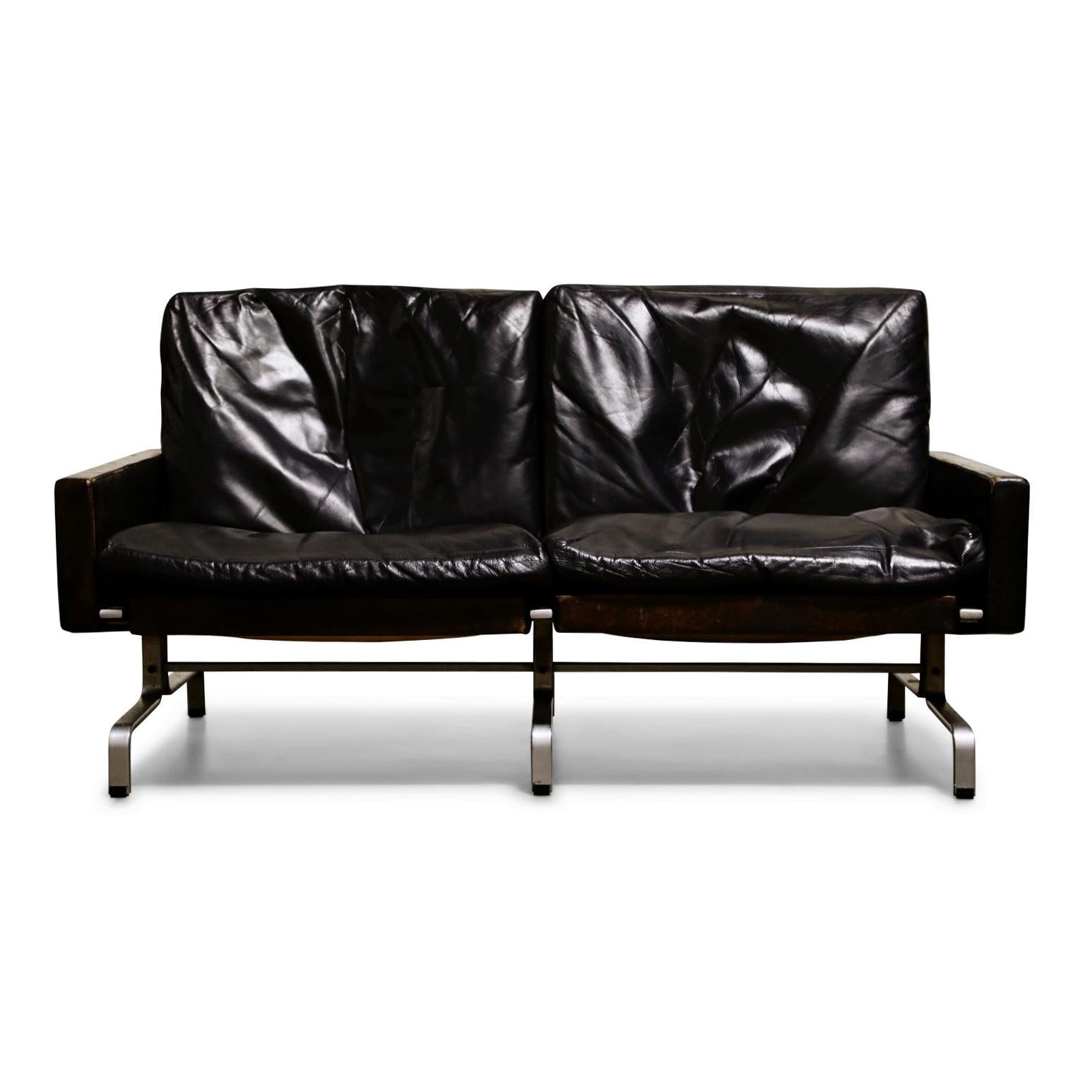 This highly collected and coveted early production example PK 31 loveseat by Poul Kjærholm for E. Kold Christensen has lovely aged black leather. Designed and produced in the 1960s in Denmark, Poul Kjaerholm was well known for precision engineering