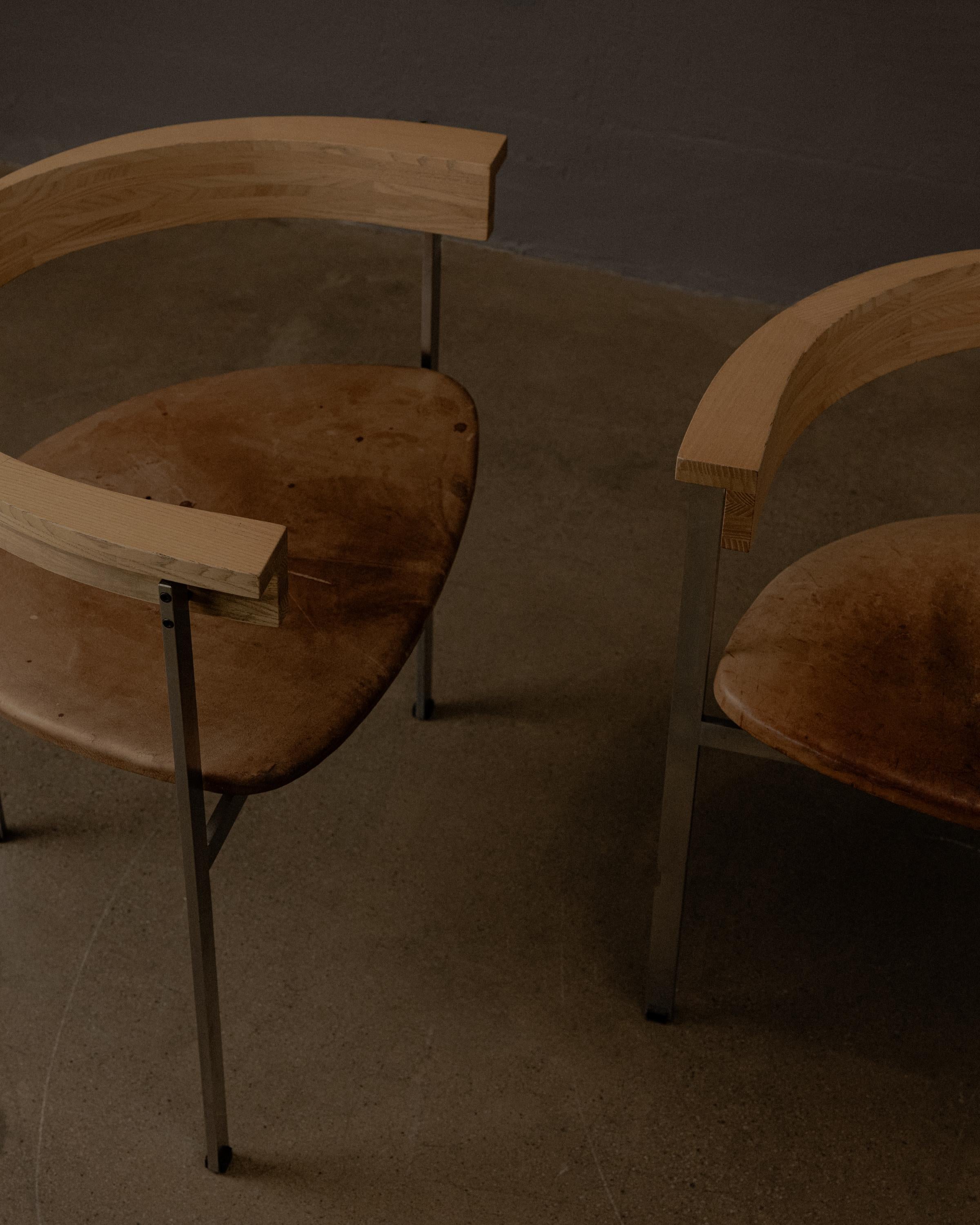 Designed by Poul Kjærholm and produced by E. Kold Christensen, this early edition features a brushed steel frame, a sculptural ash wood backrest, and a patinated leather seat.