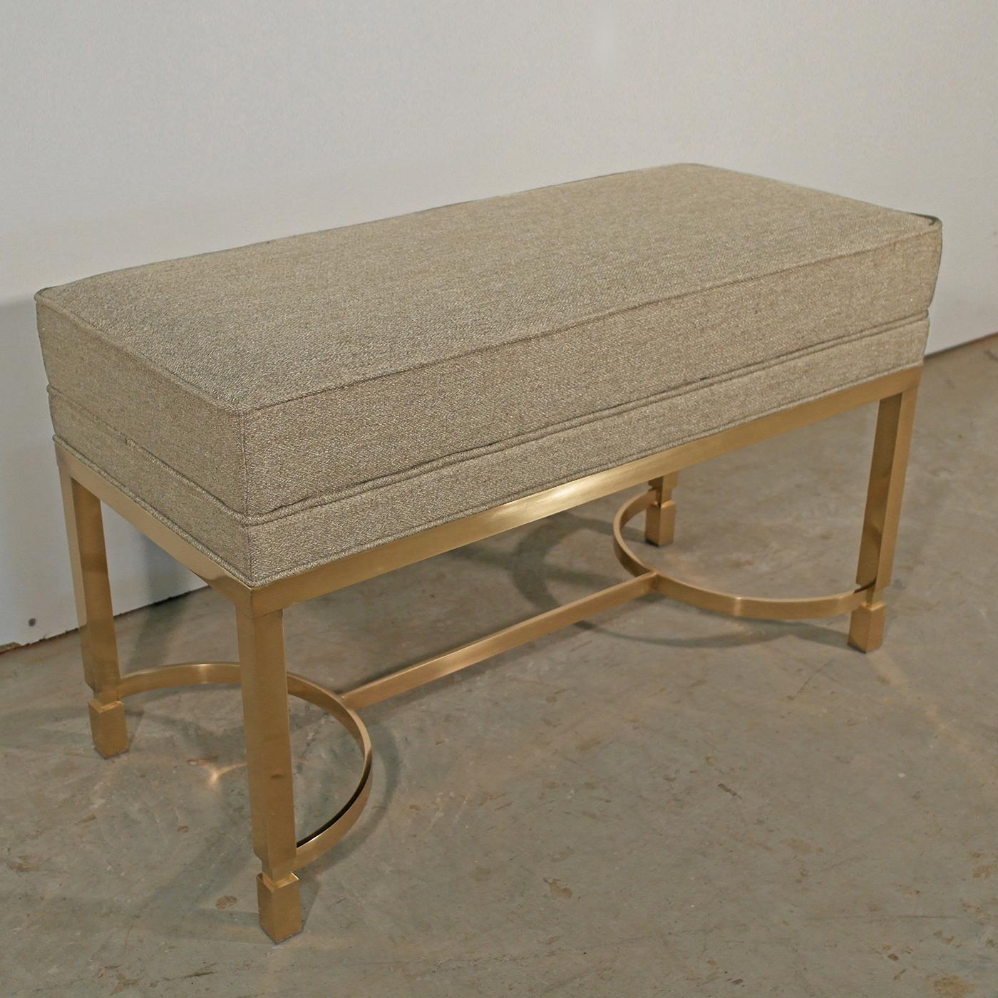 Exuding a modern elegance, this sophisticated bench is the perfect addition to the hallway or bedroom. Its polished brass base is characterized by semi-circular details, topped with a padded seat upholstered in soft gray fabric. Defined by sleek