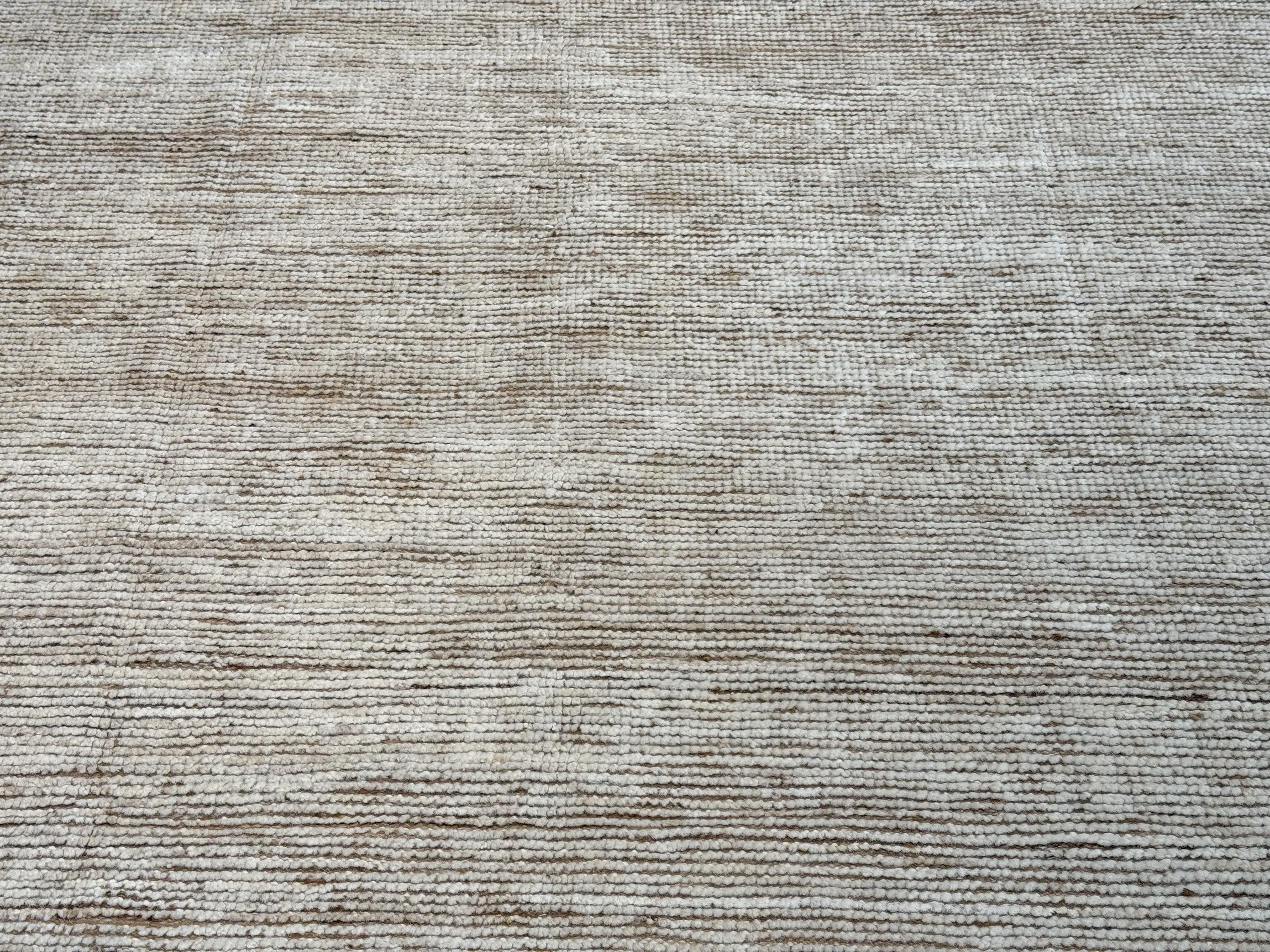 Coming from our newest collection of Moroccan G designs, this plain field with border combination Moroccan design area rug is handmade and hand-knotted made in Pakistan. It has a cotton base and is made from all goat wool yarns. It features a