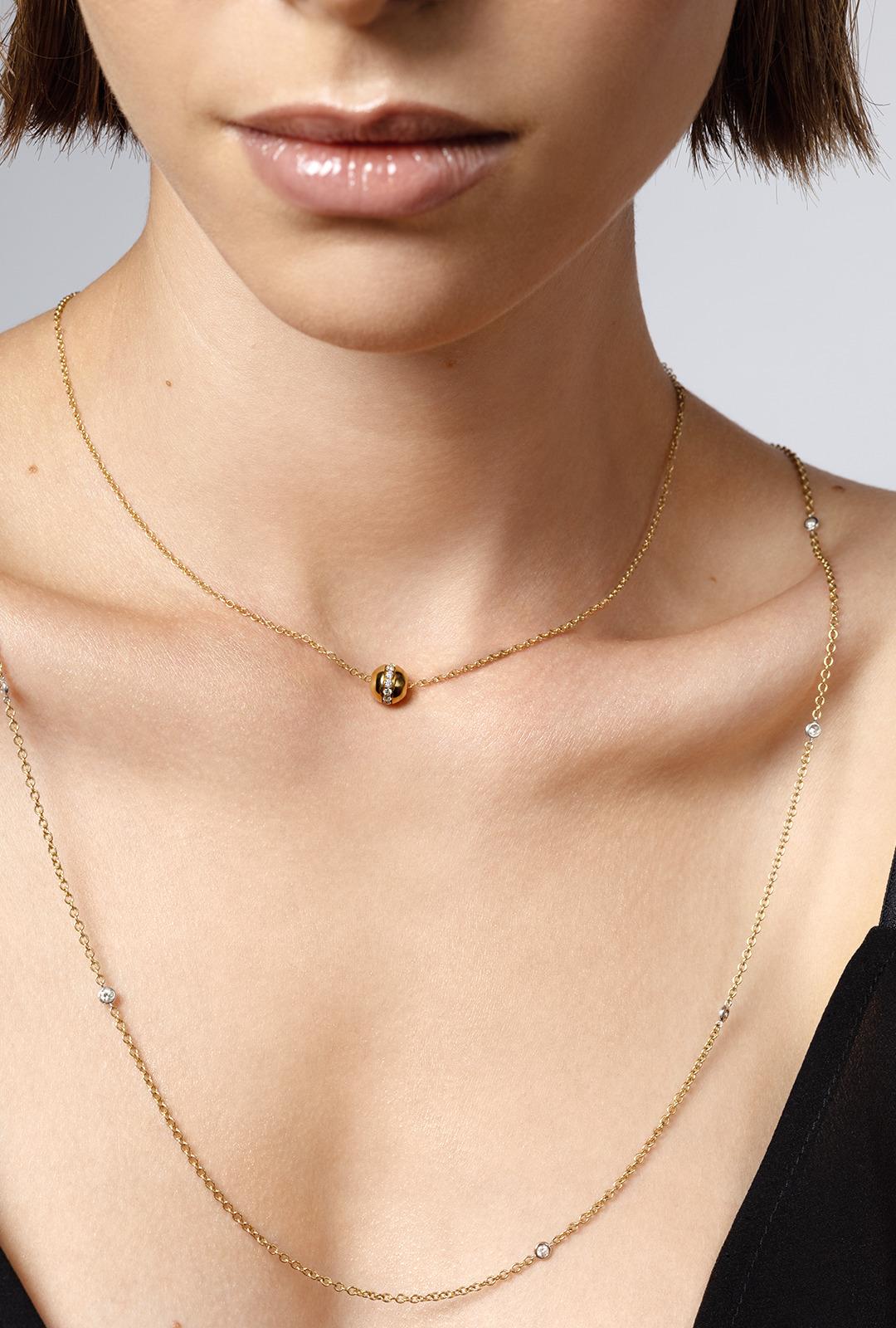 Cet élégant pendentif en or jaune dégage une sophistication intemporelle et une allure moderne. Dotée d'un design sphérique élégant, la breloque est ornée d'une rangée rayonnante de diamants scintillants qui divisent gracieusement le pendentif,